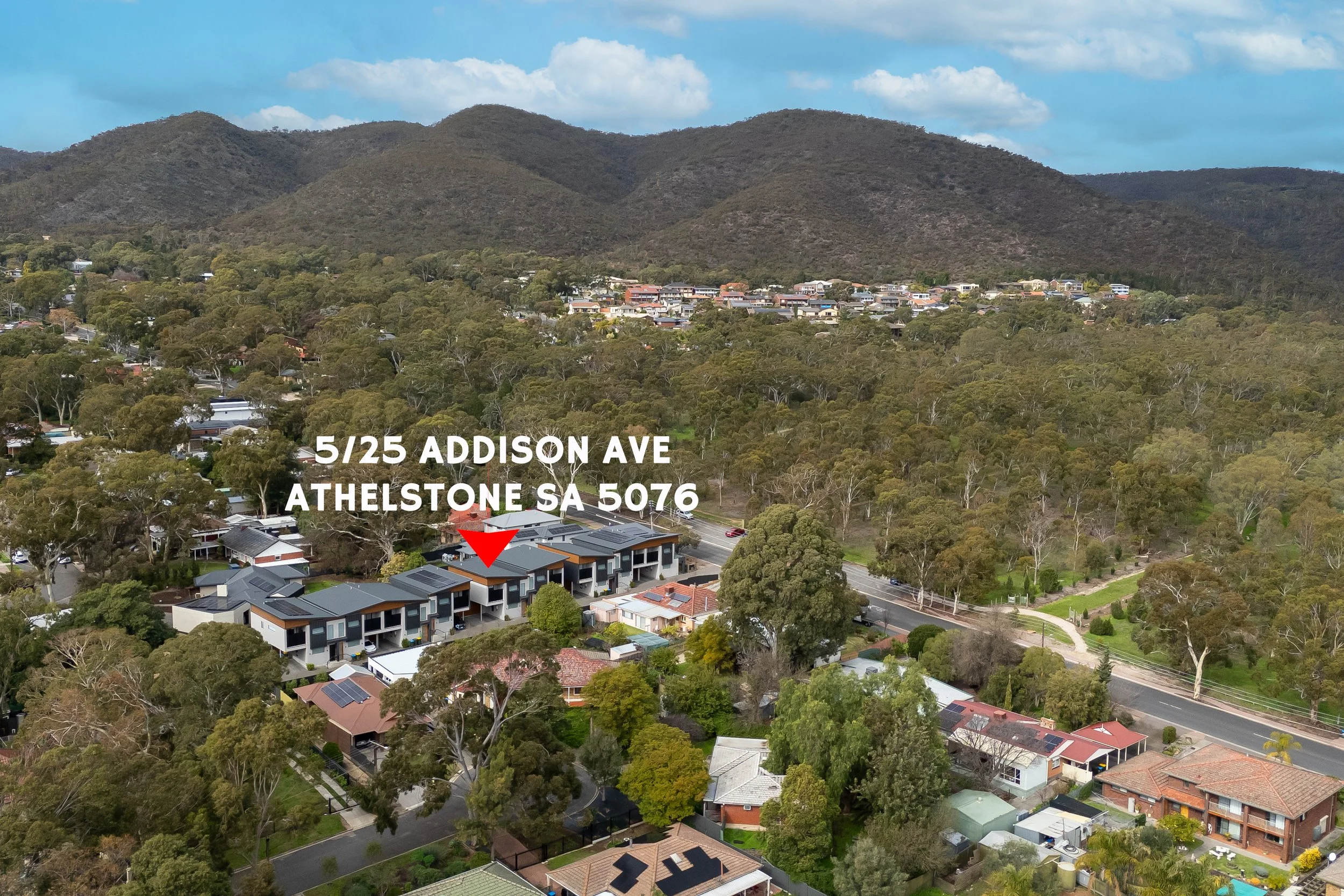 An aerial view of a residential neighborhood surrounded by trees, with hills in the background and a partly cloudy sky. A red arrow points to a specific building. Address overlay reads '5/25 Addison Ave, Athelstone SA 5076.'