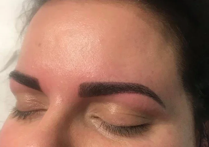 Close-up of a person's face showing freshly done eyebrow makeup with dark, well-defined, arched eyebrows and closed eyes.