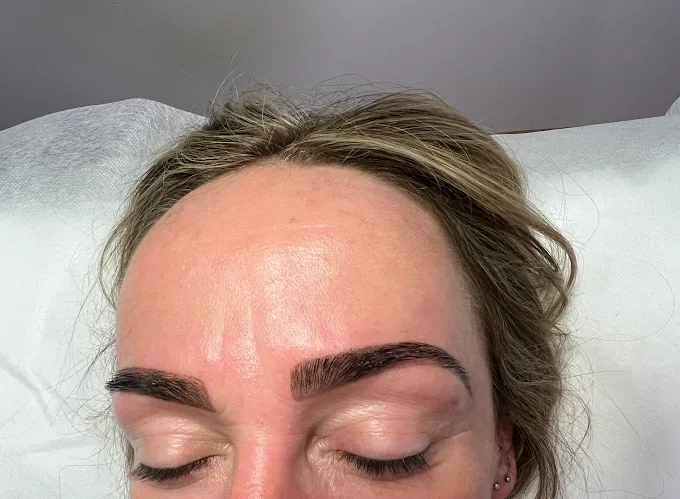 Close-up of a woman's face with makeup, lying down with eyes closed, on a white pillow.