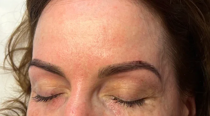 Close-up of a woman's face with her eyes closed, showing her eyebrows and forehead.