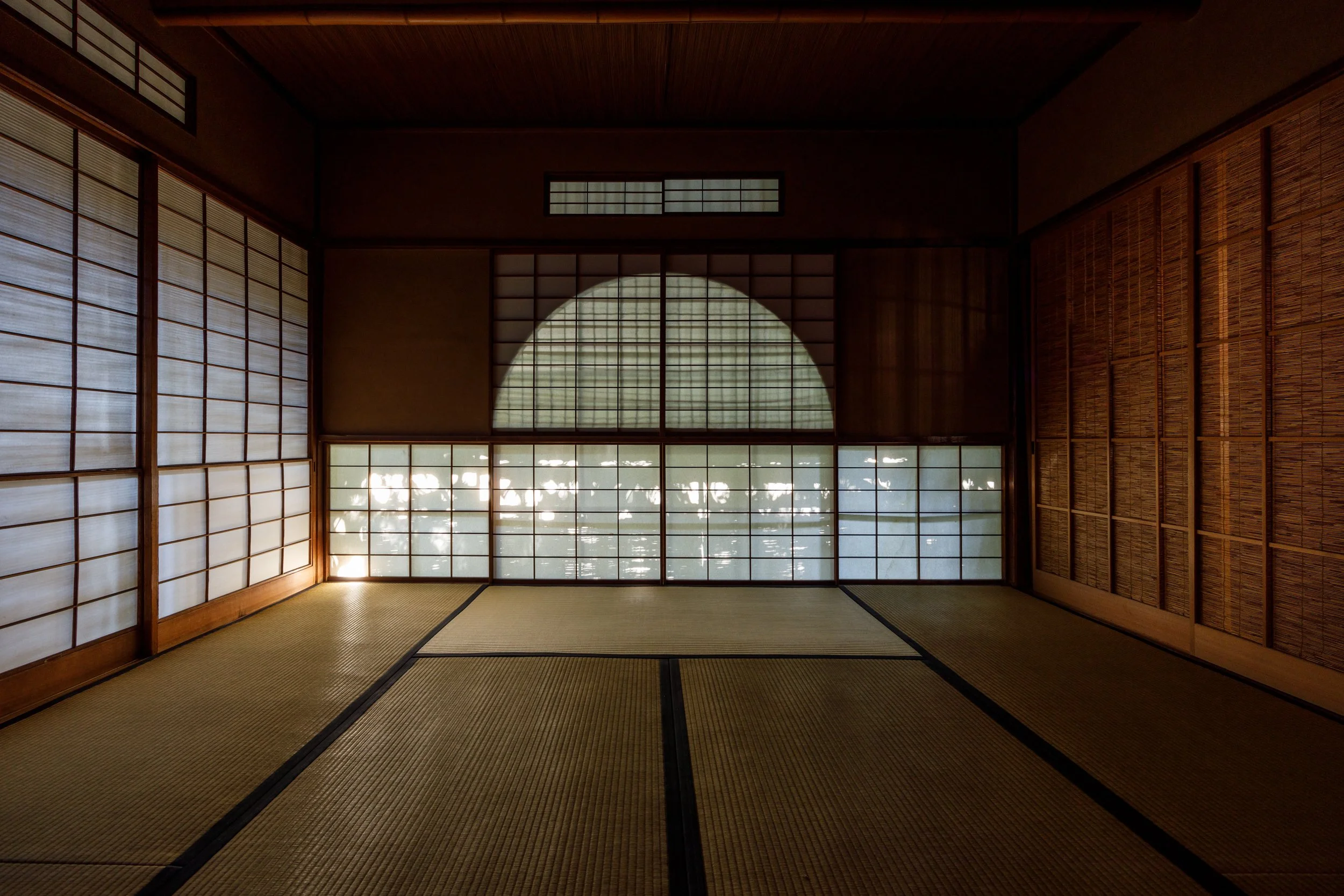  山吹 ― 親しい集いの場 
 
「山吹」は、親密で気軽な茶の湯の場のために特別に設計された、小ぶりで内輪向きの茶室です。
この八畳間は、参加者同士に温かさと親しみの感覚をもたらすよう意図されており、茶の湯において重んじられる人と人との調和の精神を静かに体現しています。床脇には、繰り抜いた壁に十一本の矢羽を配列する特徴的な意匠が目を引きます。