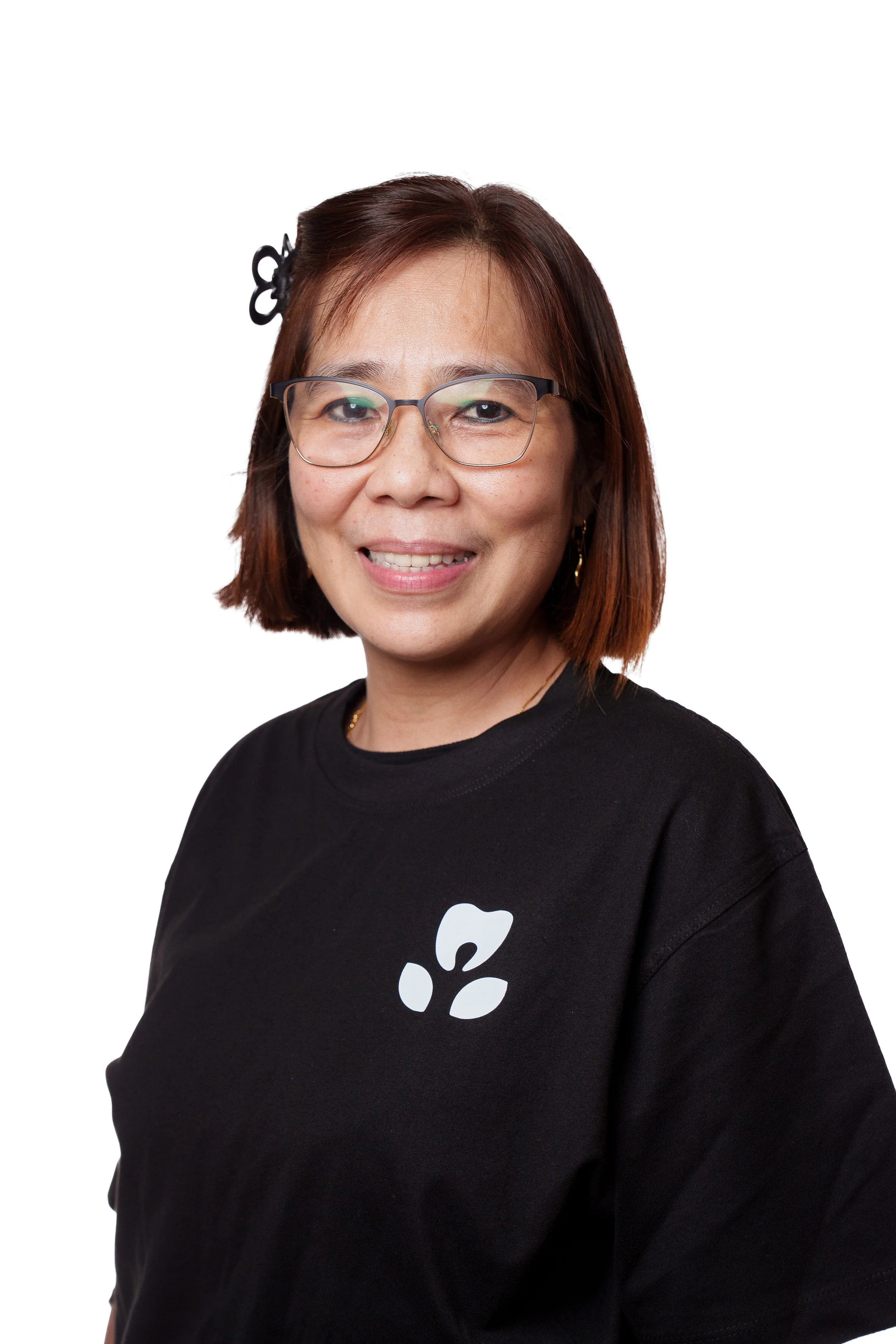 smiling woman with glasses and short auburn hair, wearing a black t-shirt with a white floral design, against a white background