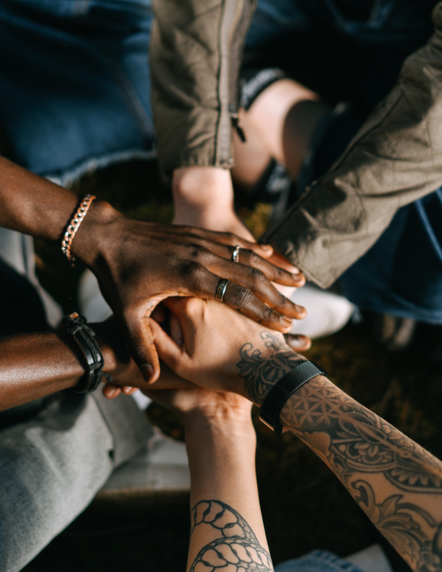 Multiple diverse hands stacked together in a show of unity and teamwork.
