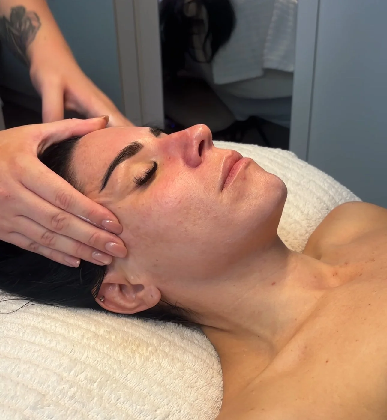 A woman receiving a facial massage in a spa or clinic setting.