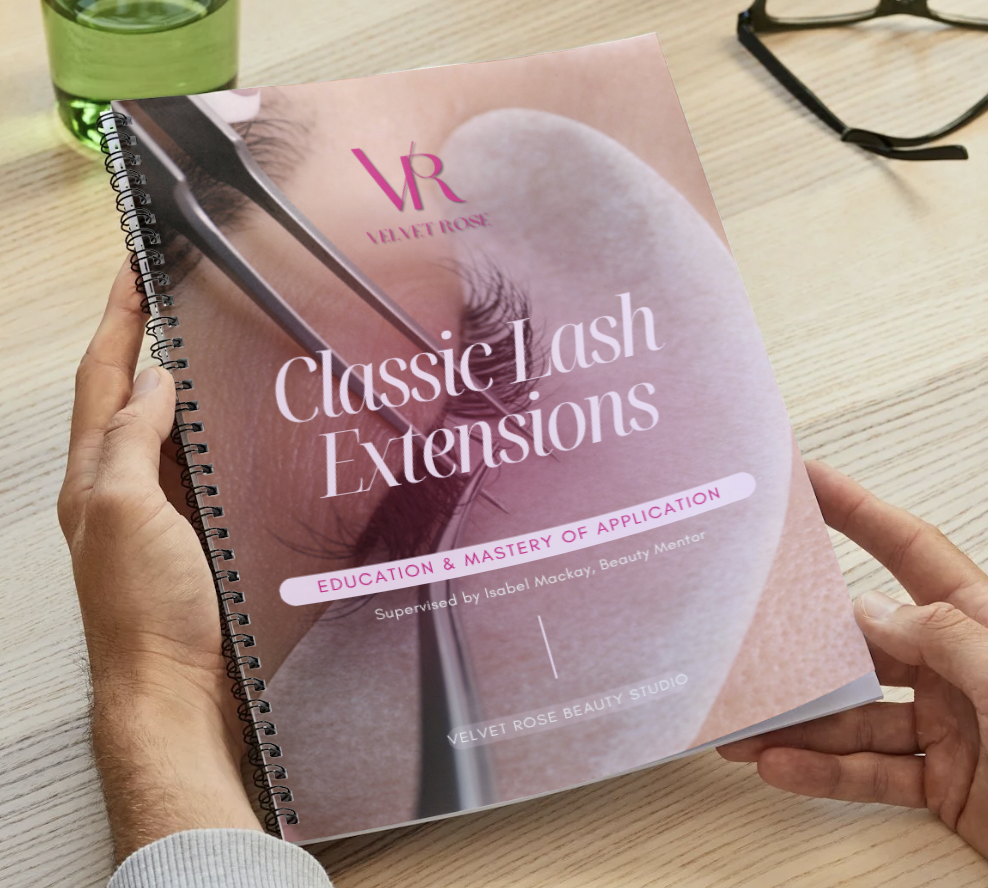 A person holding a spiral-bound course book titled "Classic Lash Extensions" with a close-up of an eye with long lashes on the cover. The book is being read by a student looking to improve their lash skills or start their own business.