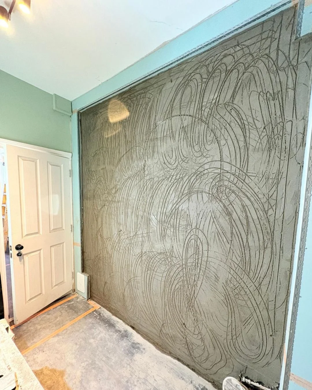 Bathroom wall with drywall, pencil sketches, and partially installed door.
