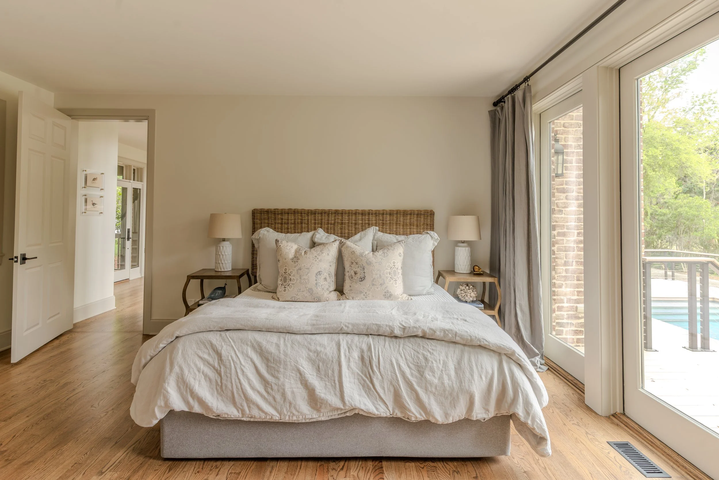 Bedroom with a bed, nightstands, lamps, and sliding glass doors leading to an outdoor balcony with a pool.