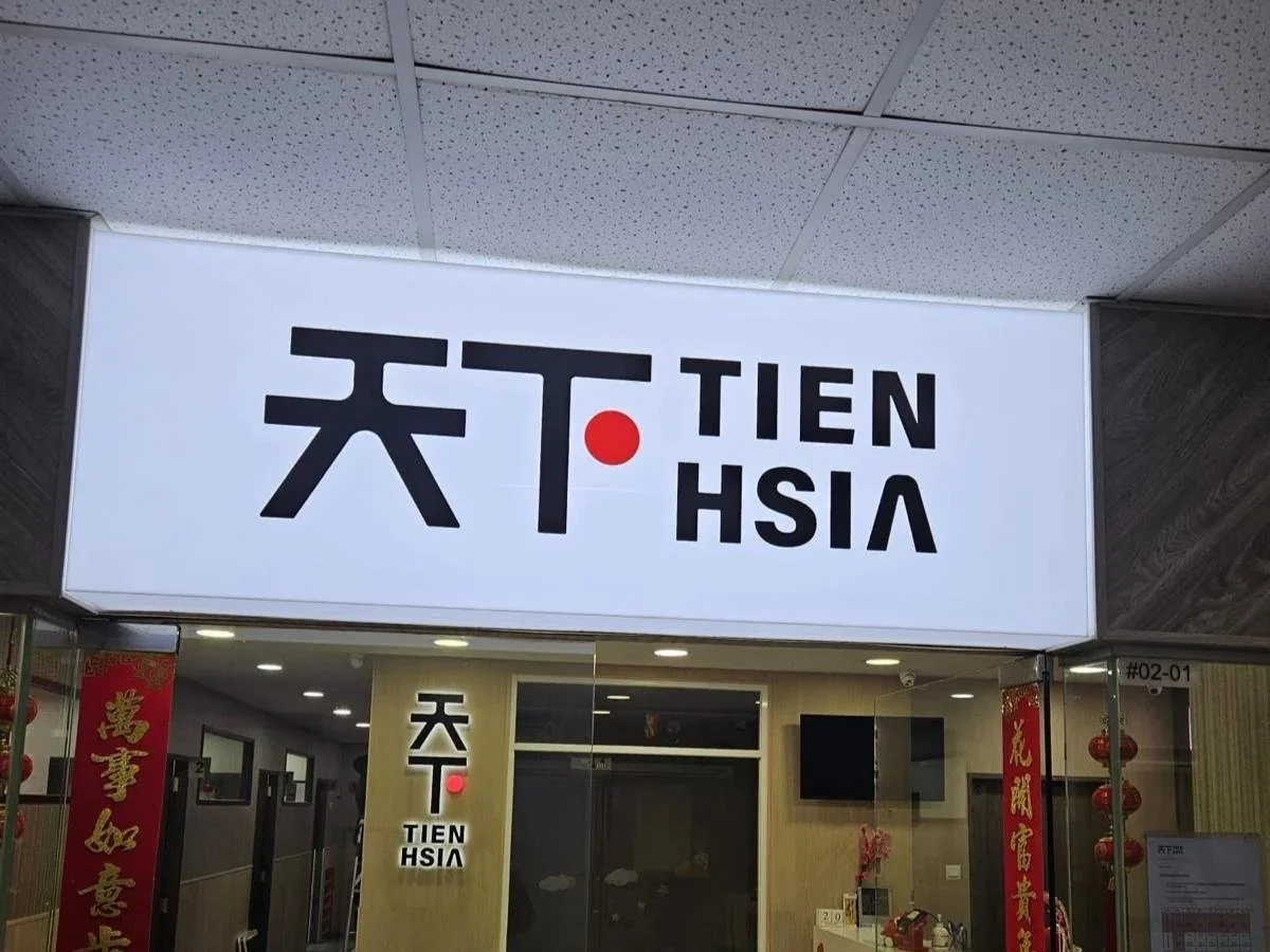 Signboard featuring Chinese characters, with the words 'TIEN HSIA' in Latin letters and a red dot in the middle.