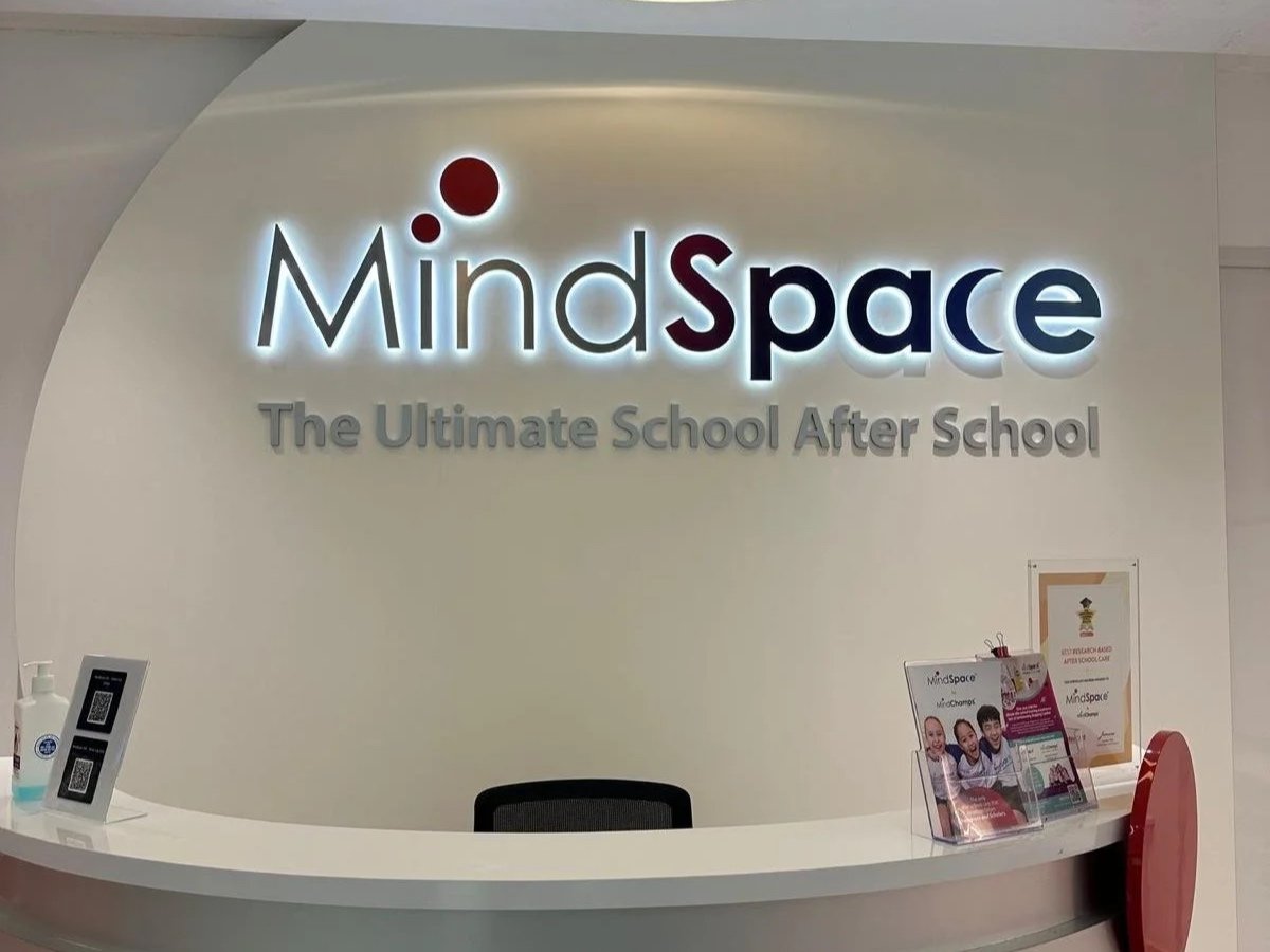 Reception area with a sign that reads 'MindSpace, The Ultimate School / After School', featuring a white counter, a sanitizer, and brochures.