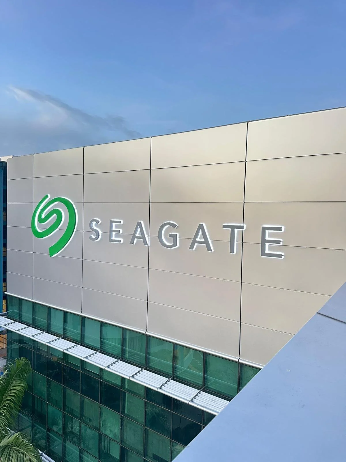 Exterior of a building with a large sign reading 'Seagate' and the company's green logo on a beige wall under a blue sky.