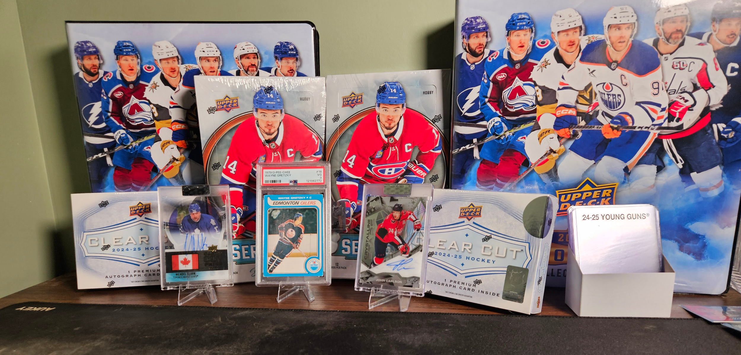 Collection of hockey memorabilia including a poster of Thunder Bay hockey players, framed rookie cards, autographed cards, and a box of hockey cards on a wooden surface. In Thunder Bay.