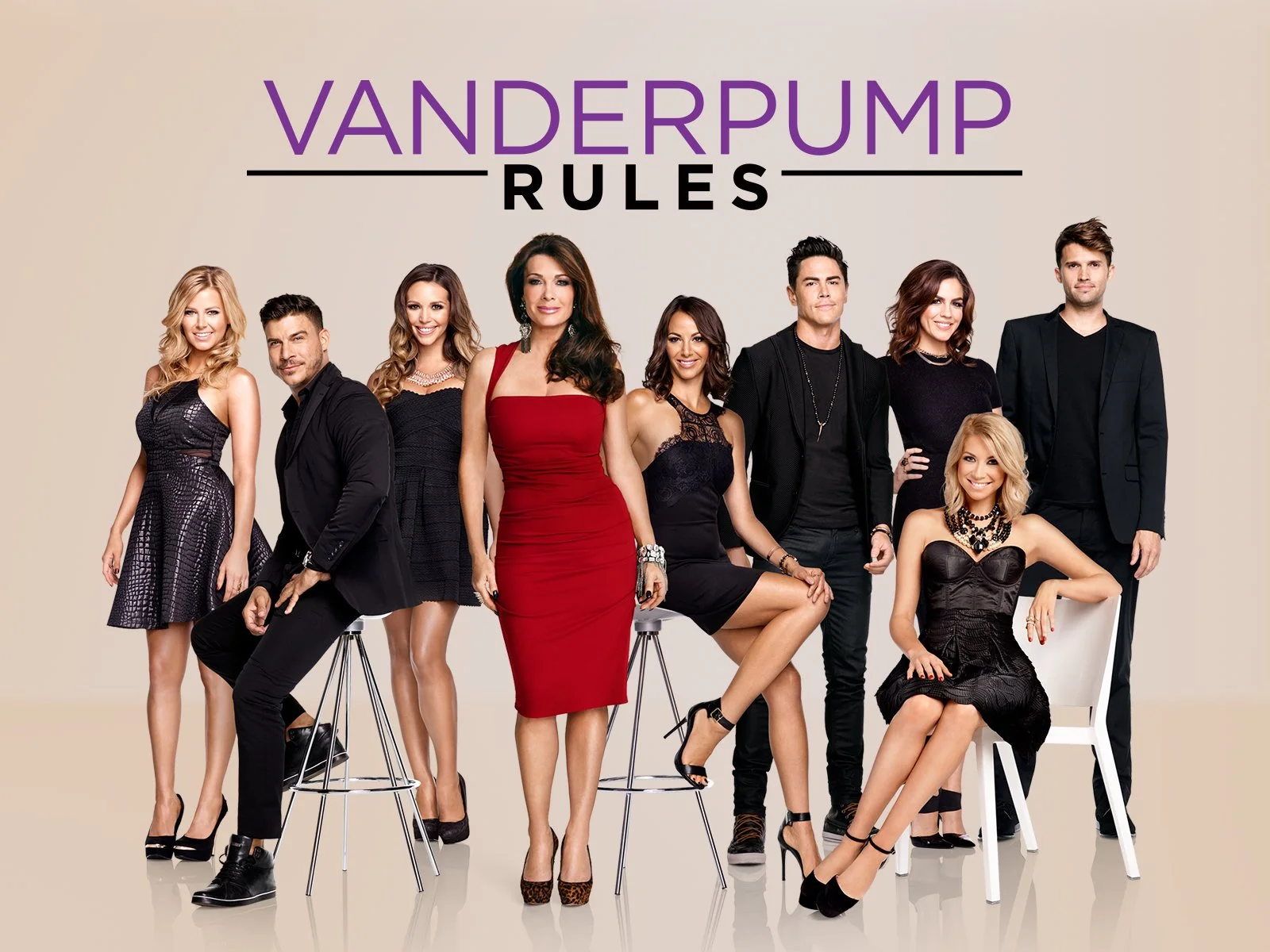 Group photo of nine people, five women and four men, dressed in fashionable black and red outfits, posing in front of a beige background with the text 'Vanderpump Rules' in purple and black.