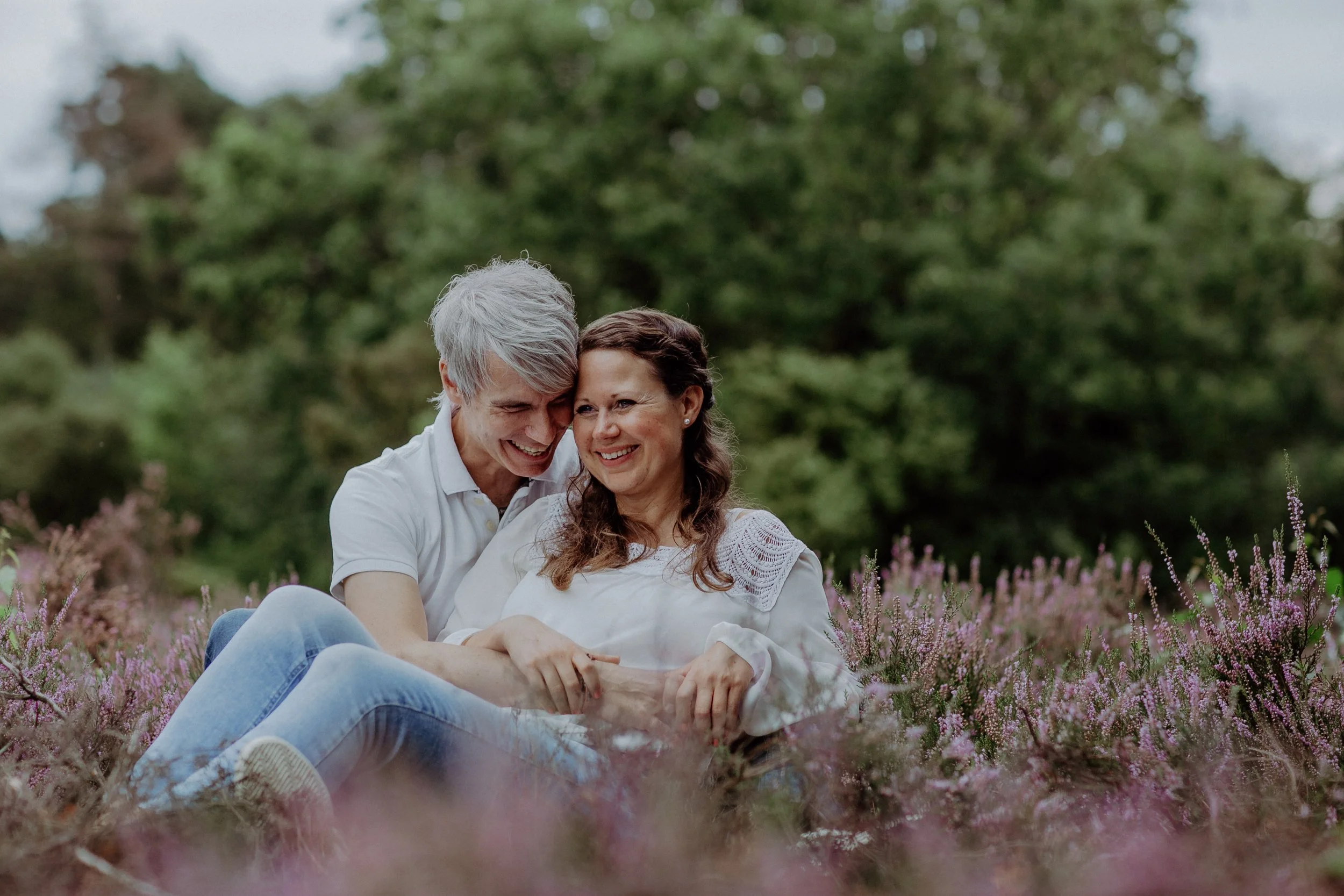 Ein älteres Paar sitzt im Blumengarten und lächelt.