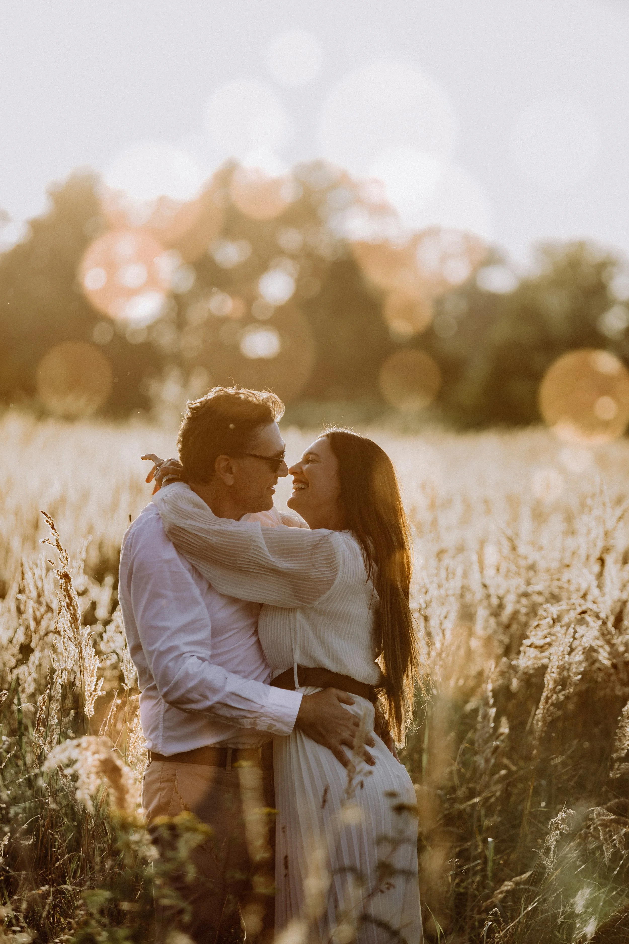 Paar umarmt sich liebevoll in einem Feld bei Sonnenuntergang
