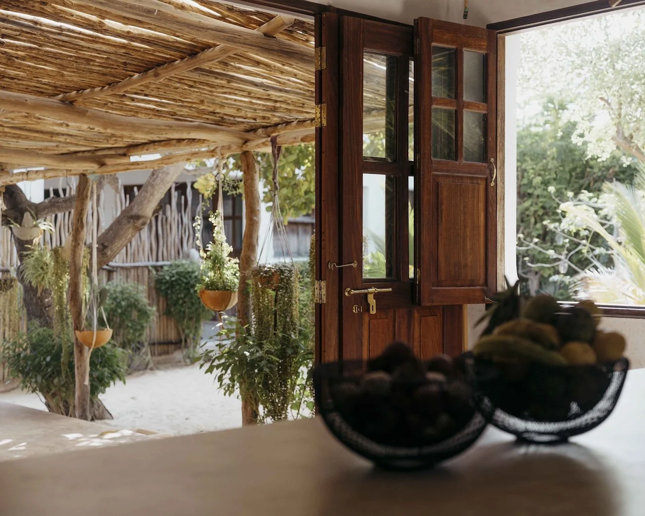 Open wooden window with garden view, hanging plants, and outdoor bamboo structure with trees and greenery outside