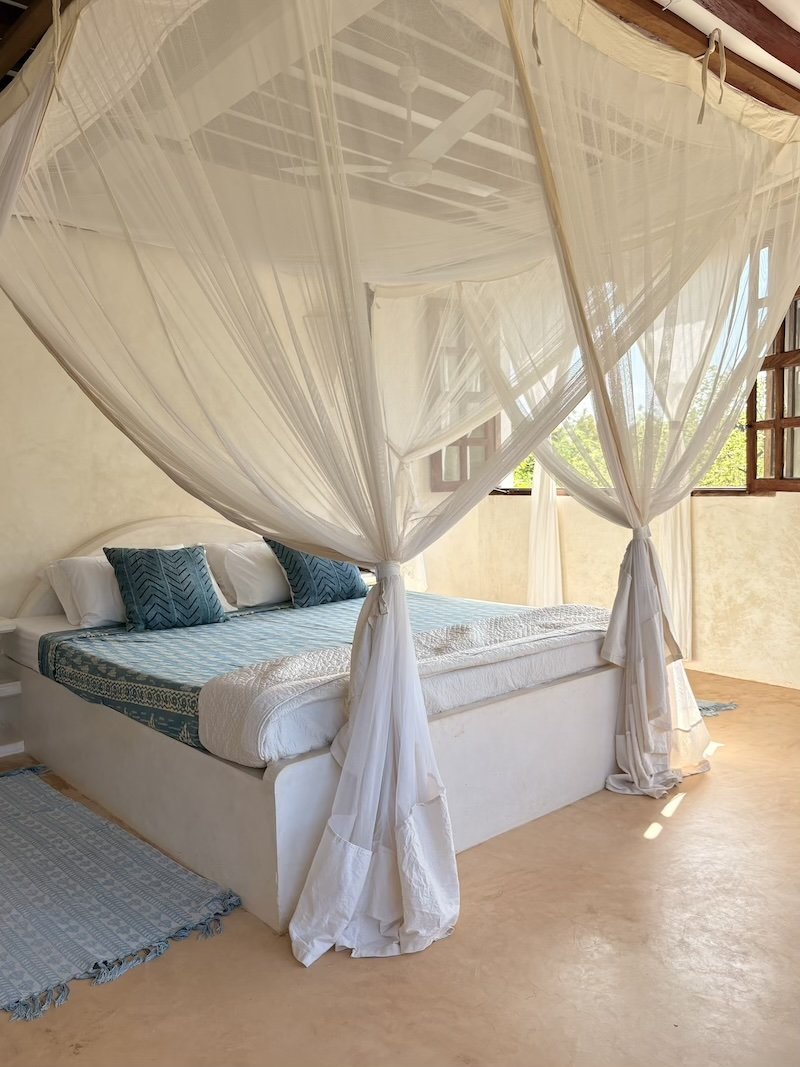a shot of a bed under a beautifully draped mosquito net