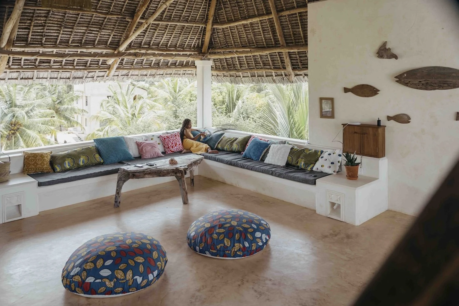 Our comfy rooftop area filled with comfortable seating, cushions and a woman reading a book and relaxing.