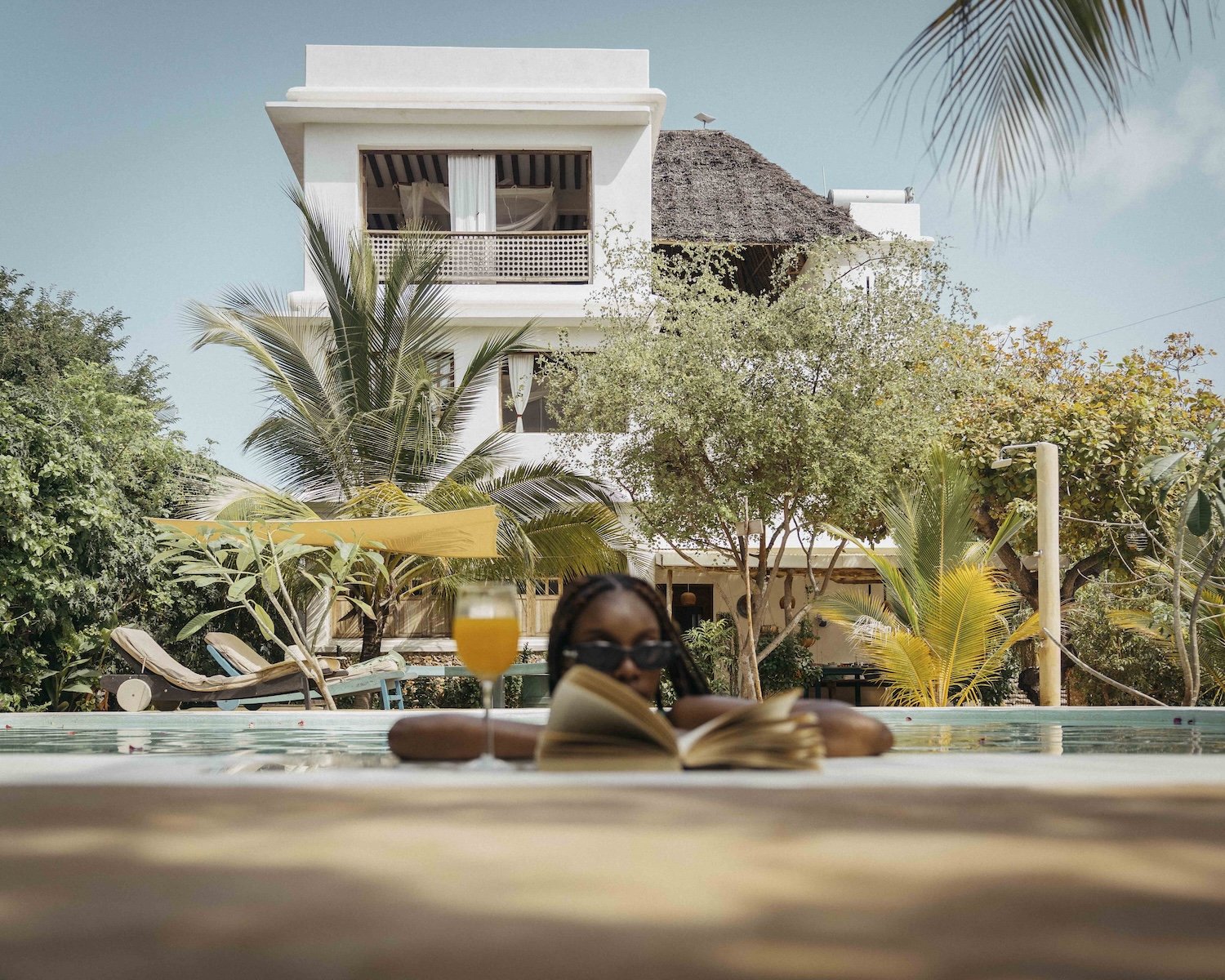 Woman reading in the pool with Mbibo House in the background