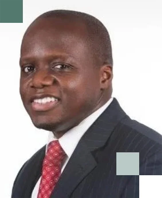 A portrait of a man in a dark business suit, white shirt, and red patterned tie, smiling at the camera.