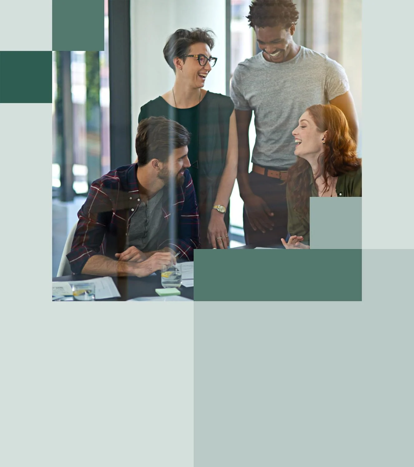 Five people laughing and engaging during a meeting in an office.