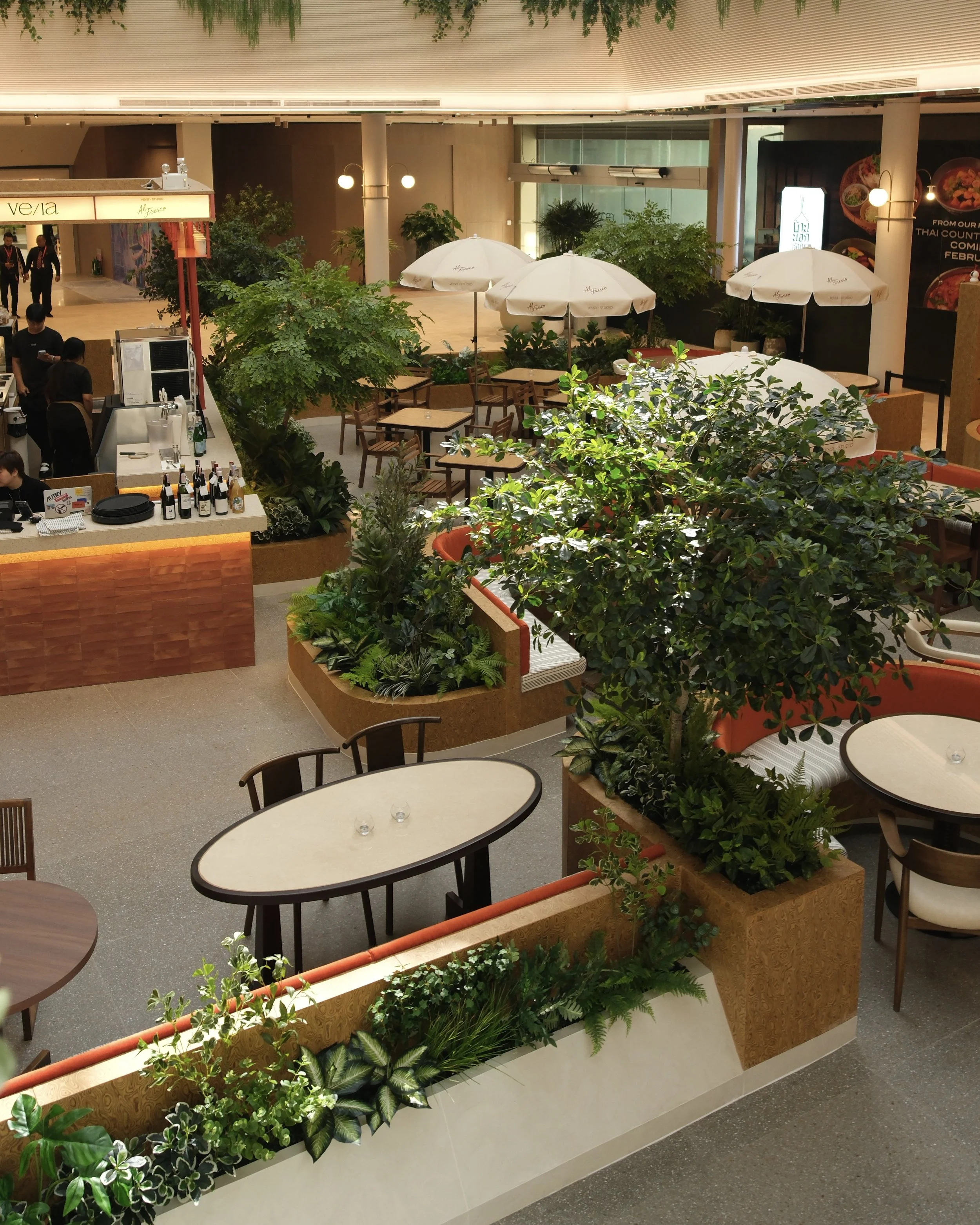Indoor dining area with tables, chairs, plants, and umbrellas