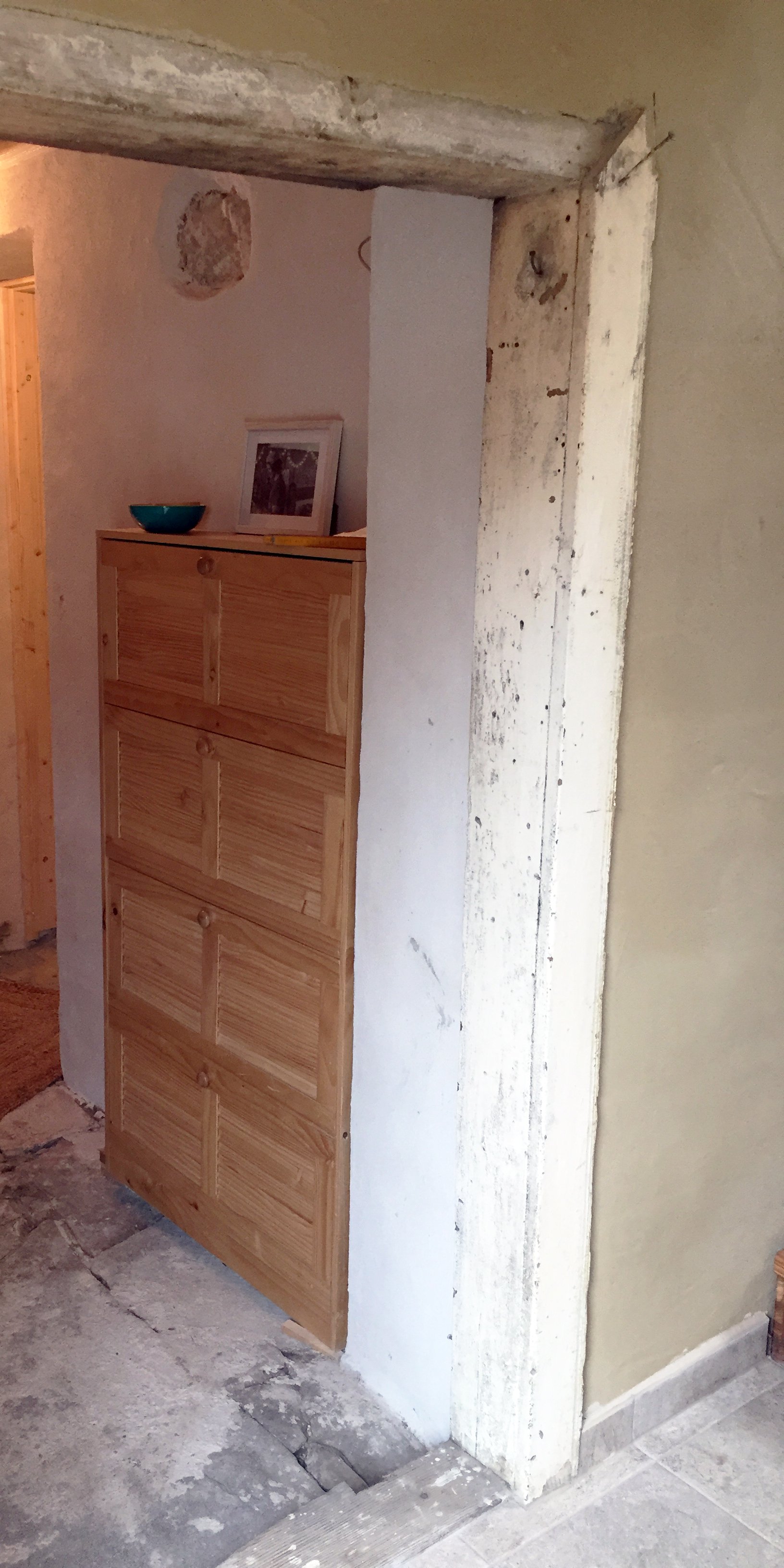 Ein alter Türstock und alter Steinboden in saniertem Haus mit Lehmwand.
