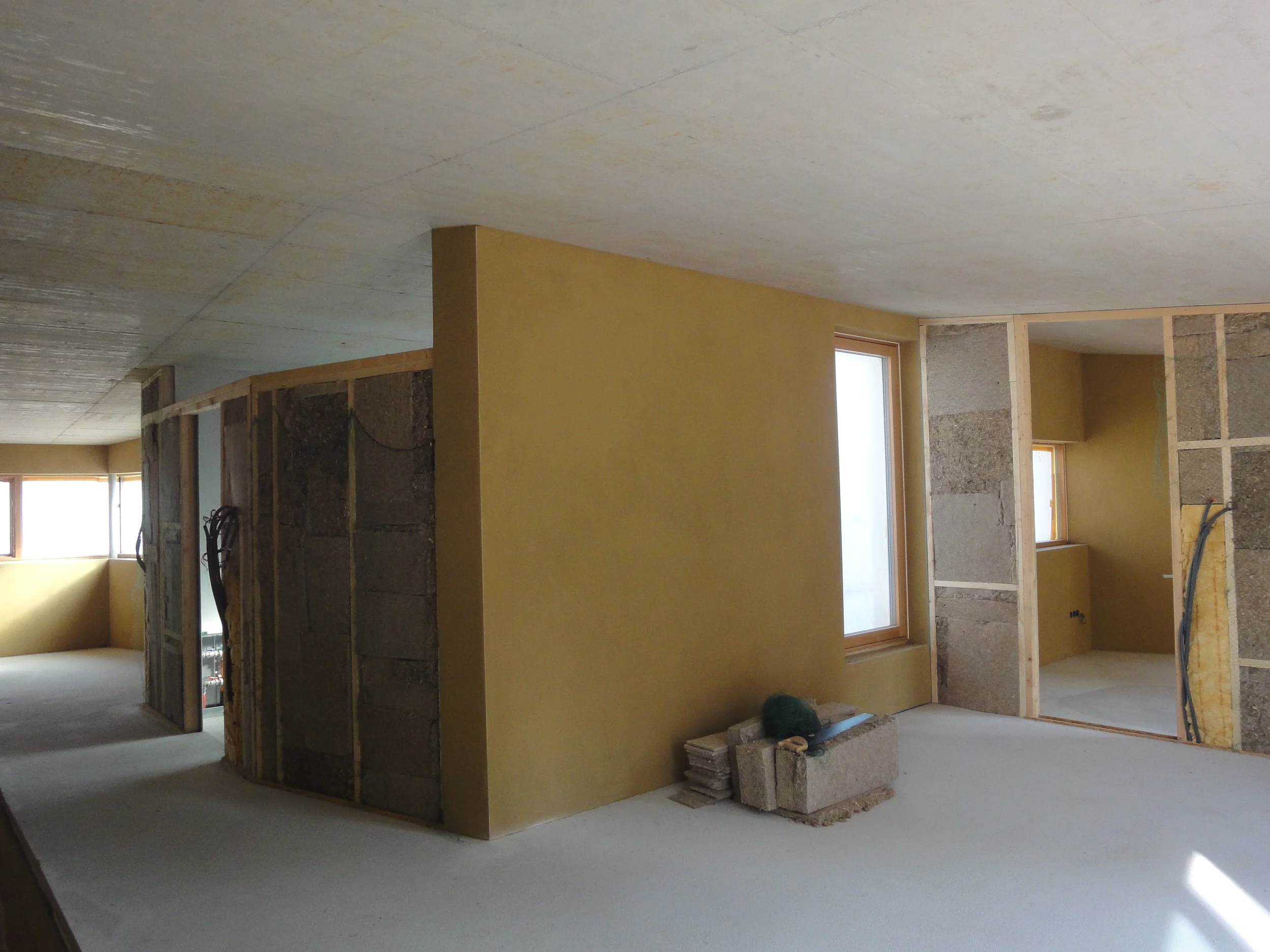 Innenraum eines Hauses unter Renovierung mit unvollständigen Wänden, Fenster und Baumaterialien auf dem Boden.