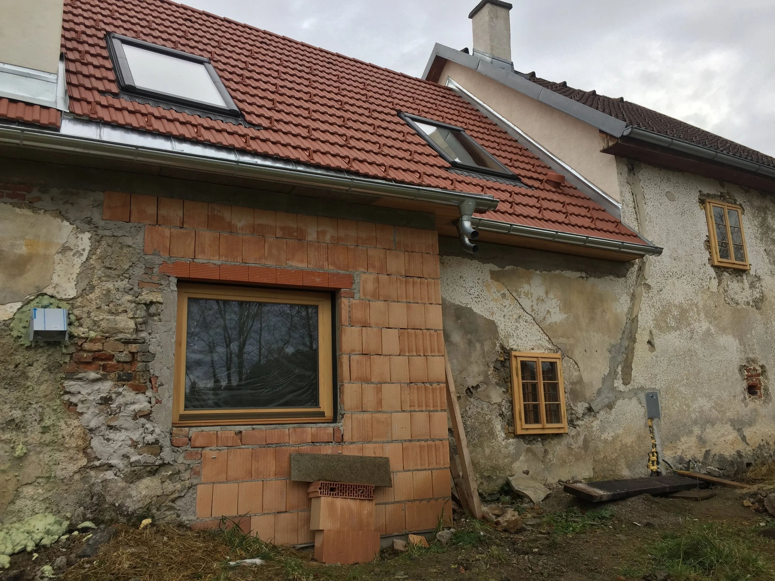 Ein Haus wird renoviert, mit teilweise abgebröckelter Fassade und neuen Fenstern sowie Dachrinnen.