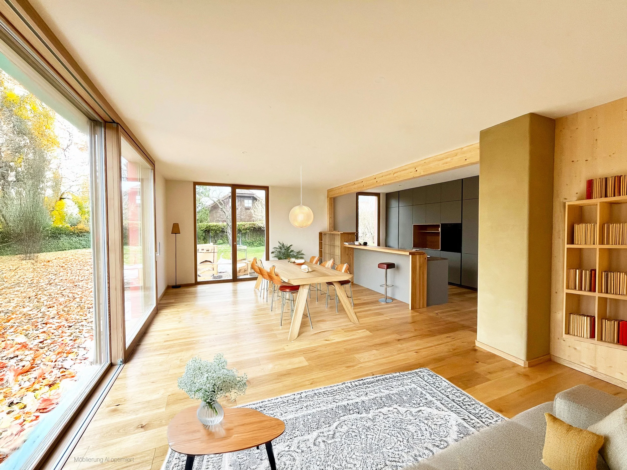 Ein offener, modern eingerichteter Wohn- und Essbereich mit großen Glasfenstern und Holzfußboden, Blick auf einen Garten im Herbst, Esstisch mit Stühlen, Küchenbar, Bücherregal, und dezente Beleuchtung