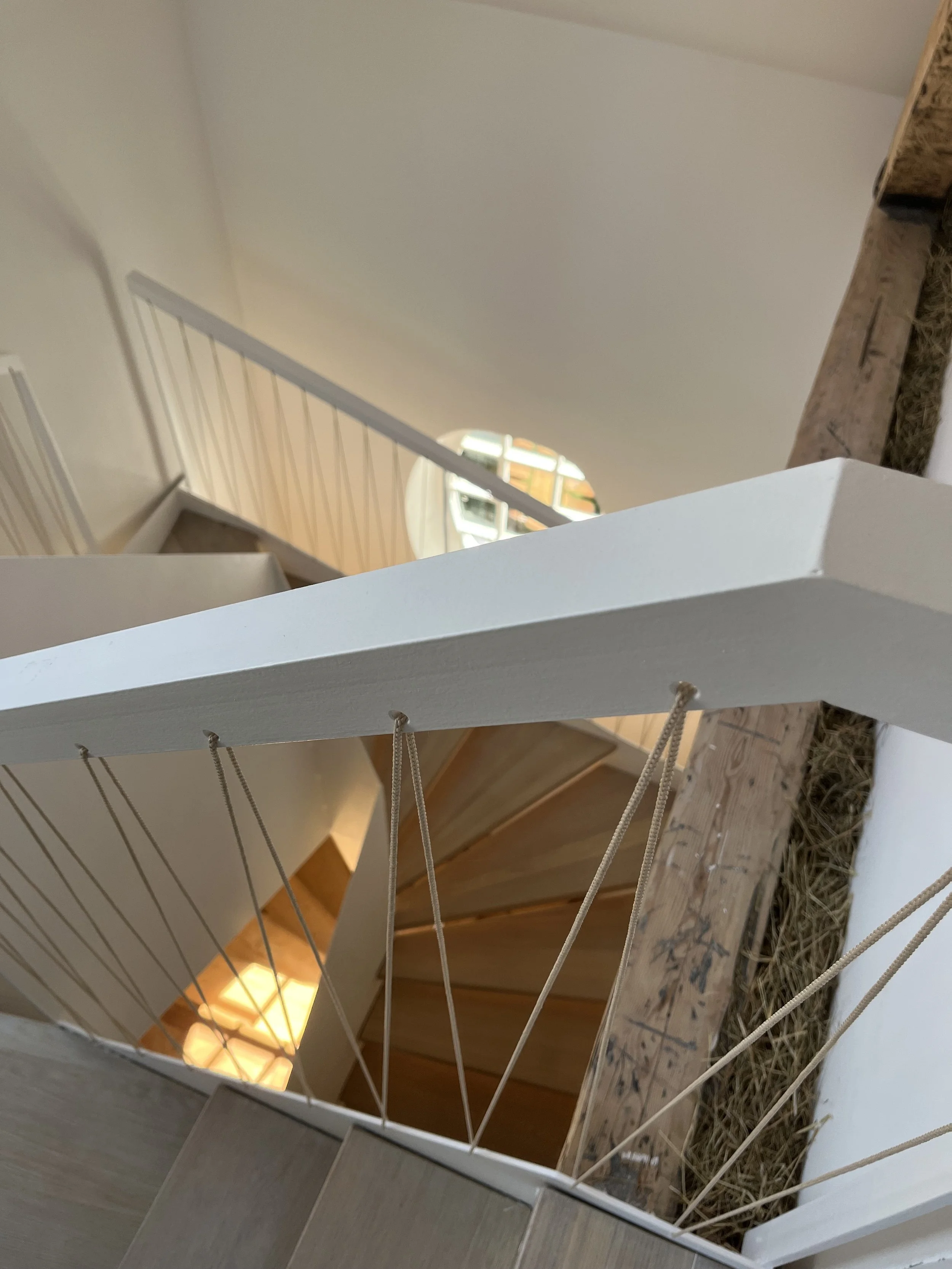 Innenaufnahme eines Treppengeländers in einem modern gestalteten Haus, Blick nach unten zu den Stufen und den Hausinnenraum.