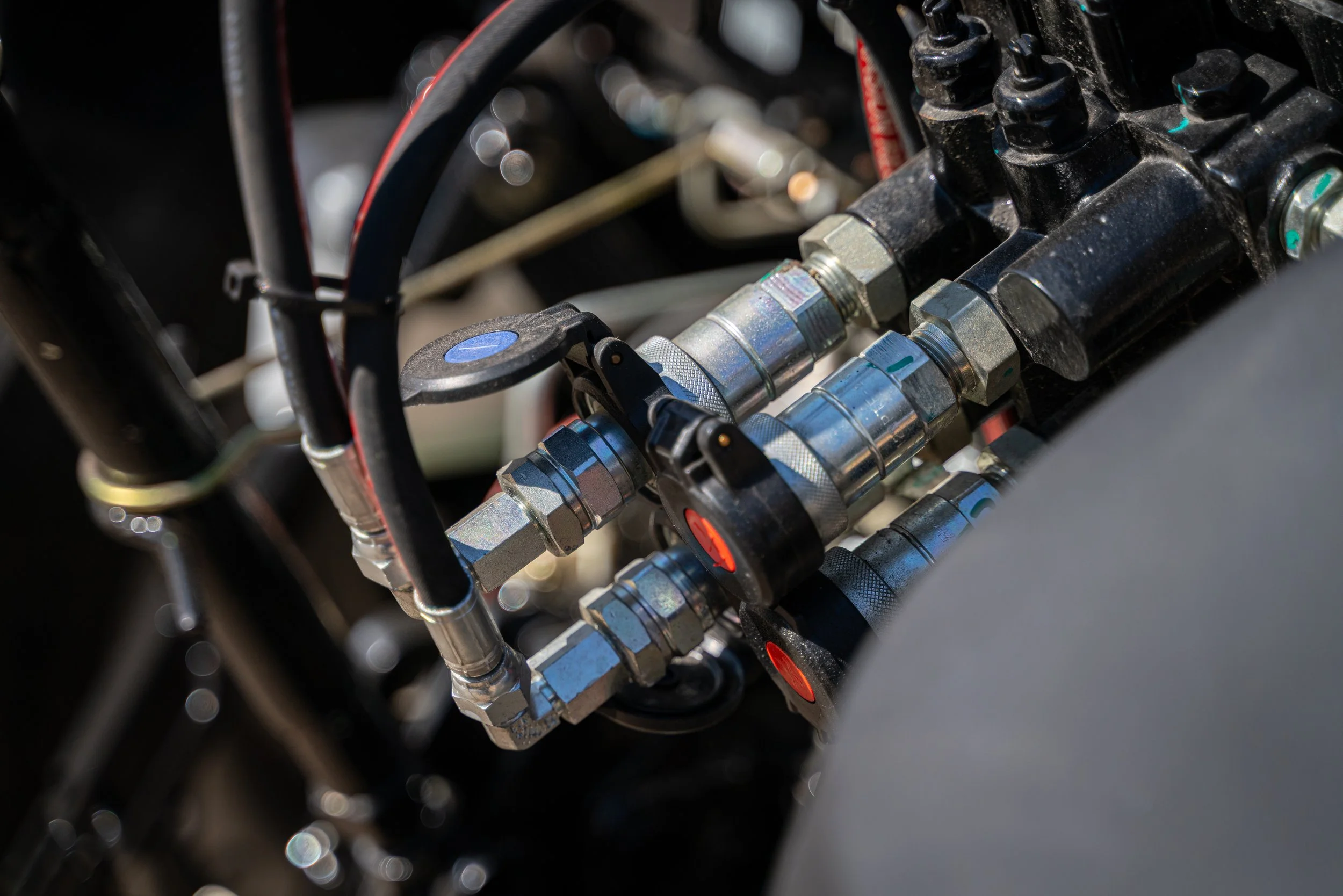 Close-up of mechanical components, including metal hoses, fittings, and black brackets, likely part of machinery or automotive system.