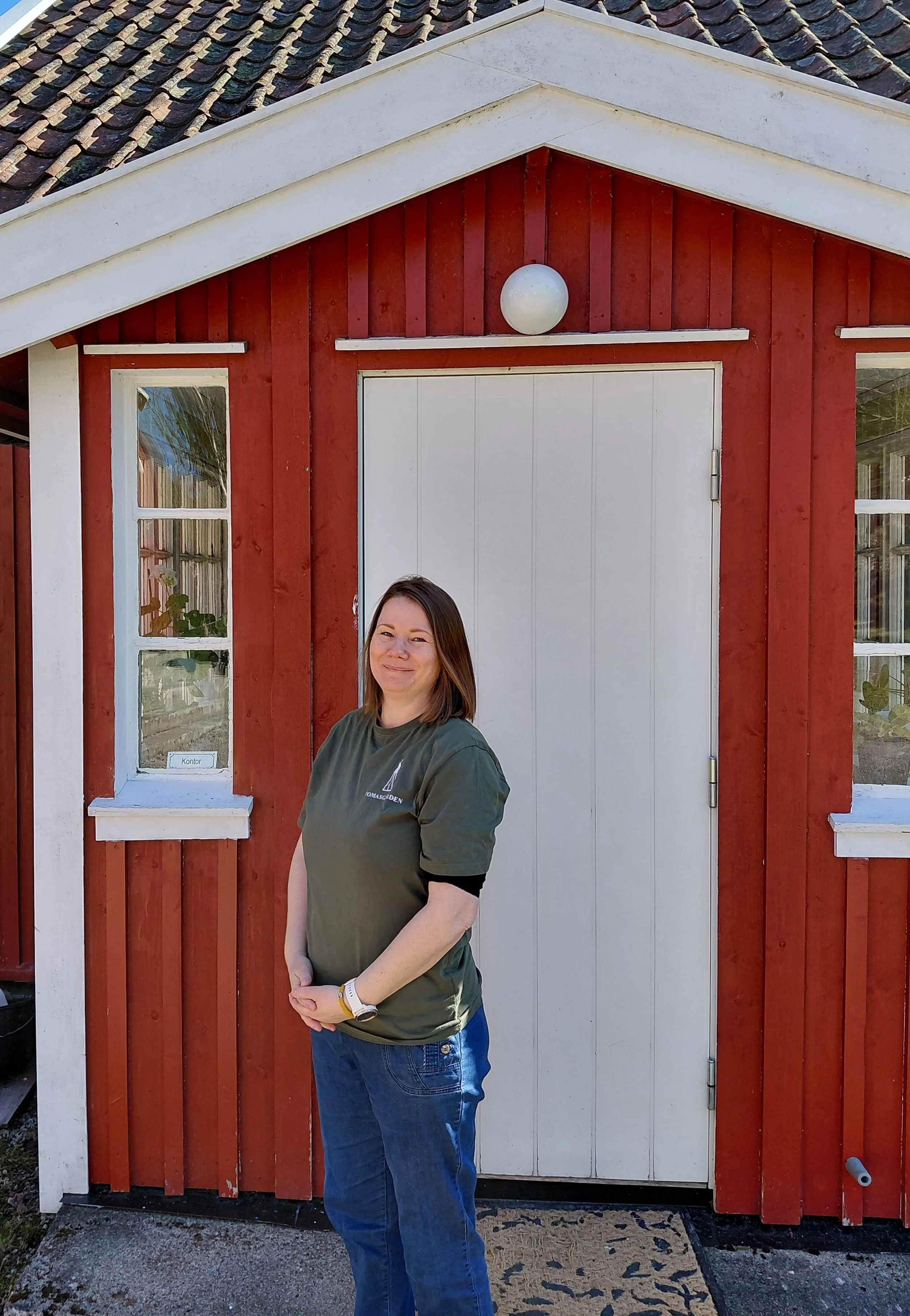 En kvinne som står foran et gammelt rødt hus