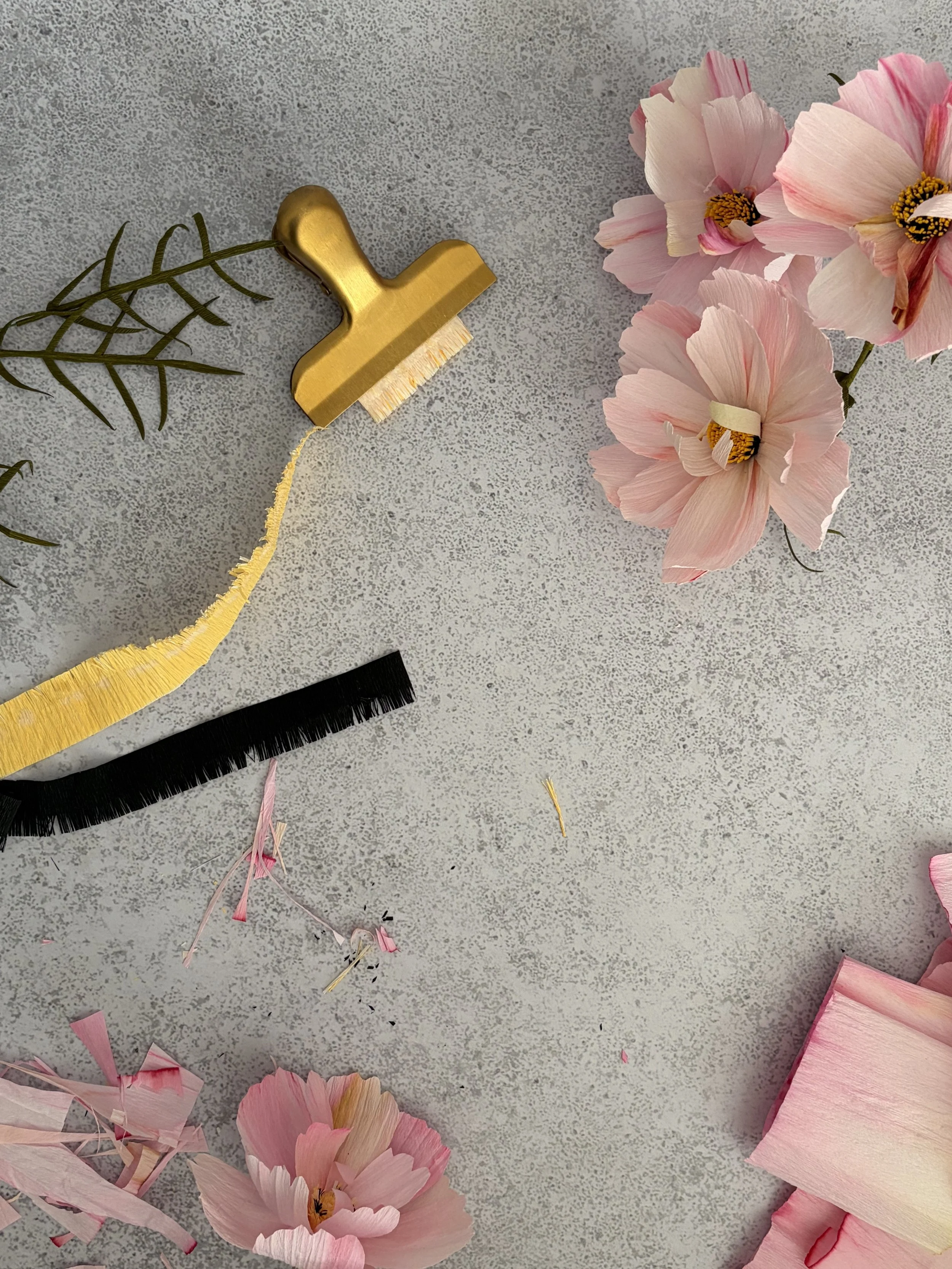 Blumen, Schere, Papierschnipsel auf einem grauen Hintergrund