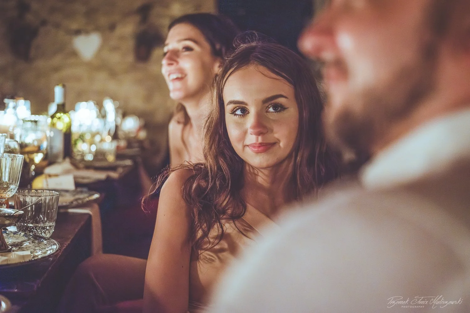 Group of people sitting at a table during a social gathering or celebration, with food and drinks visible on the table.