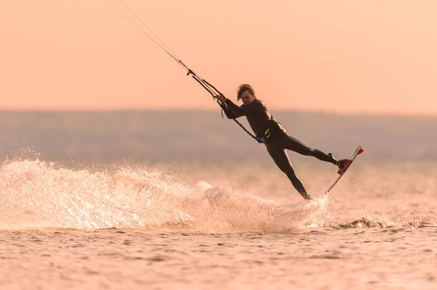 Person kite surfing on the water during sunset