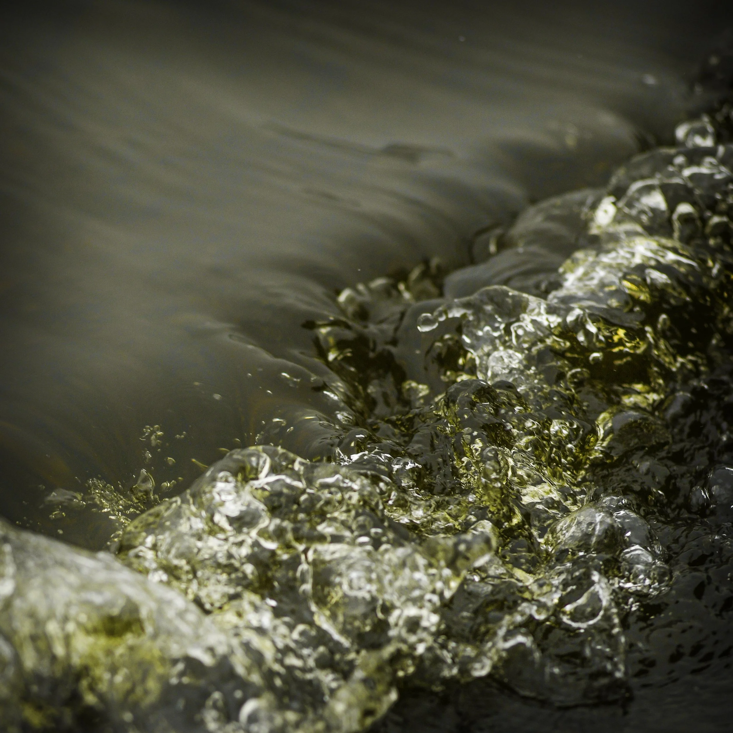 Close-up of water flowing over rocks and pebbles in a stream or river.