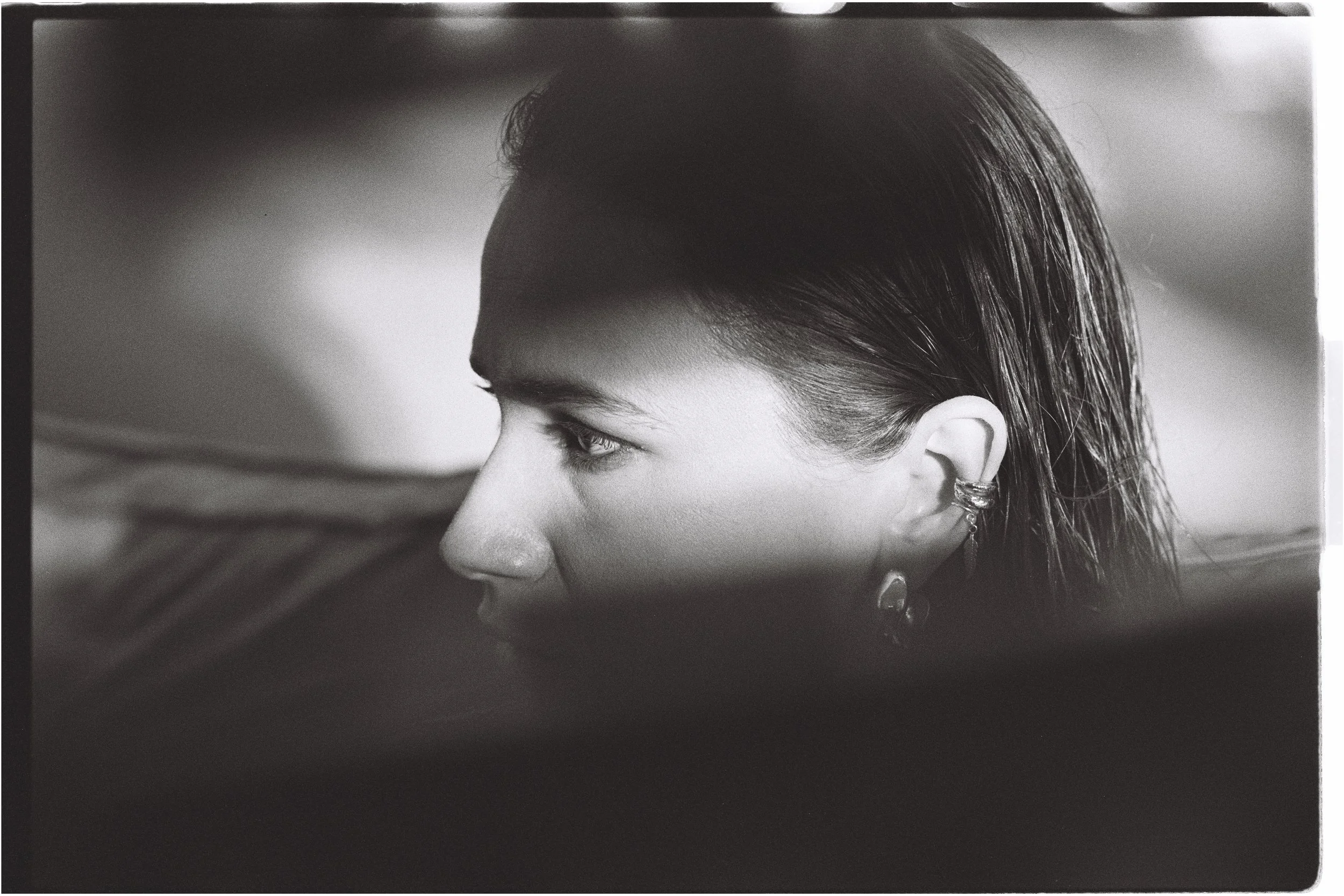 A close-up black and white photo of a woman's face in profile, showing her hair, ear, and eye.