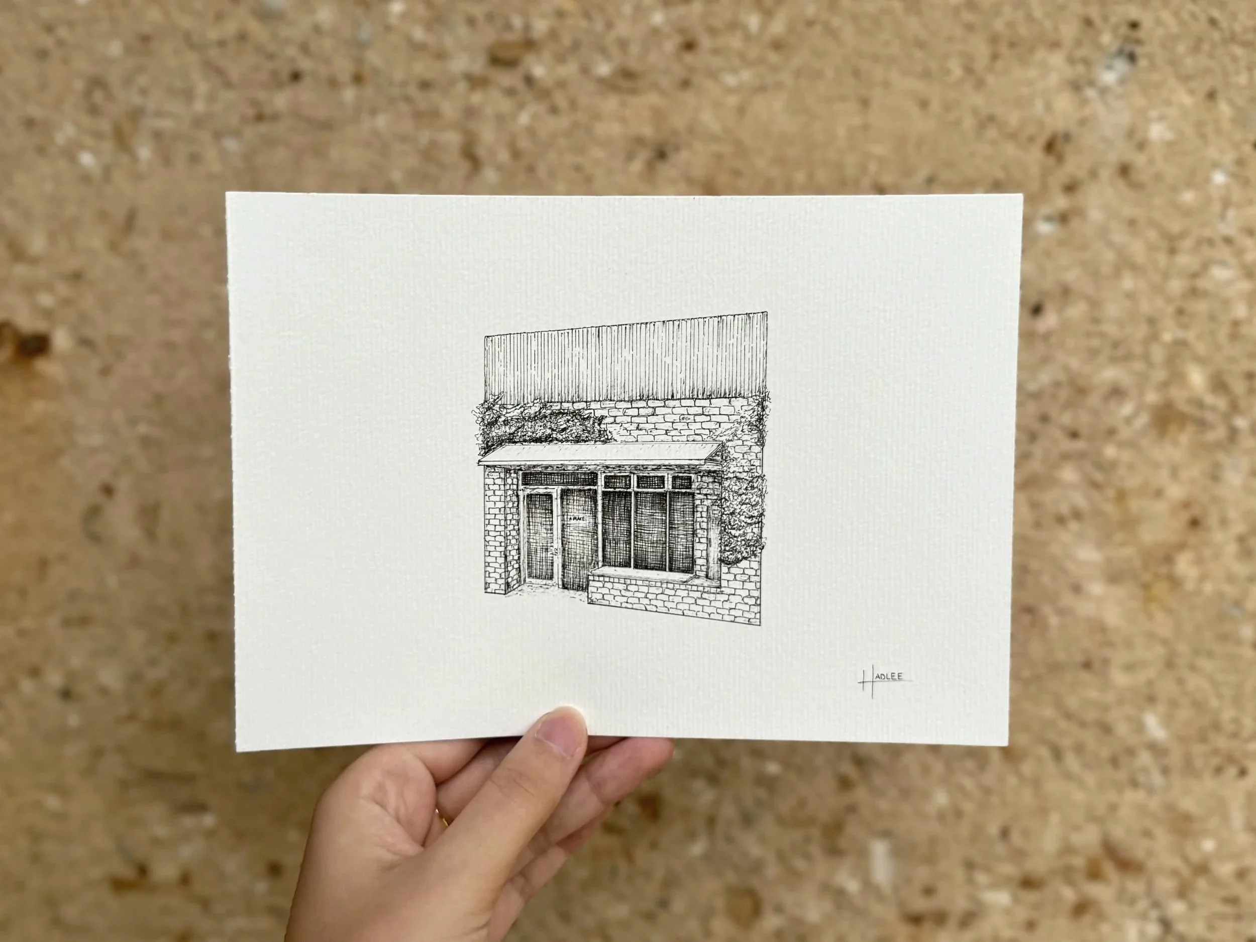 Black and white sketch of a rustic building with brick walls, a glass door, and large windows, surrounded by climbing plants.