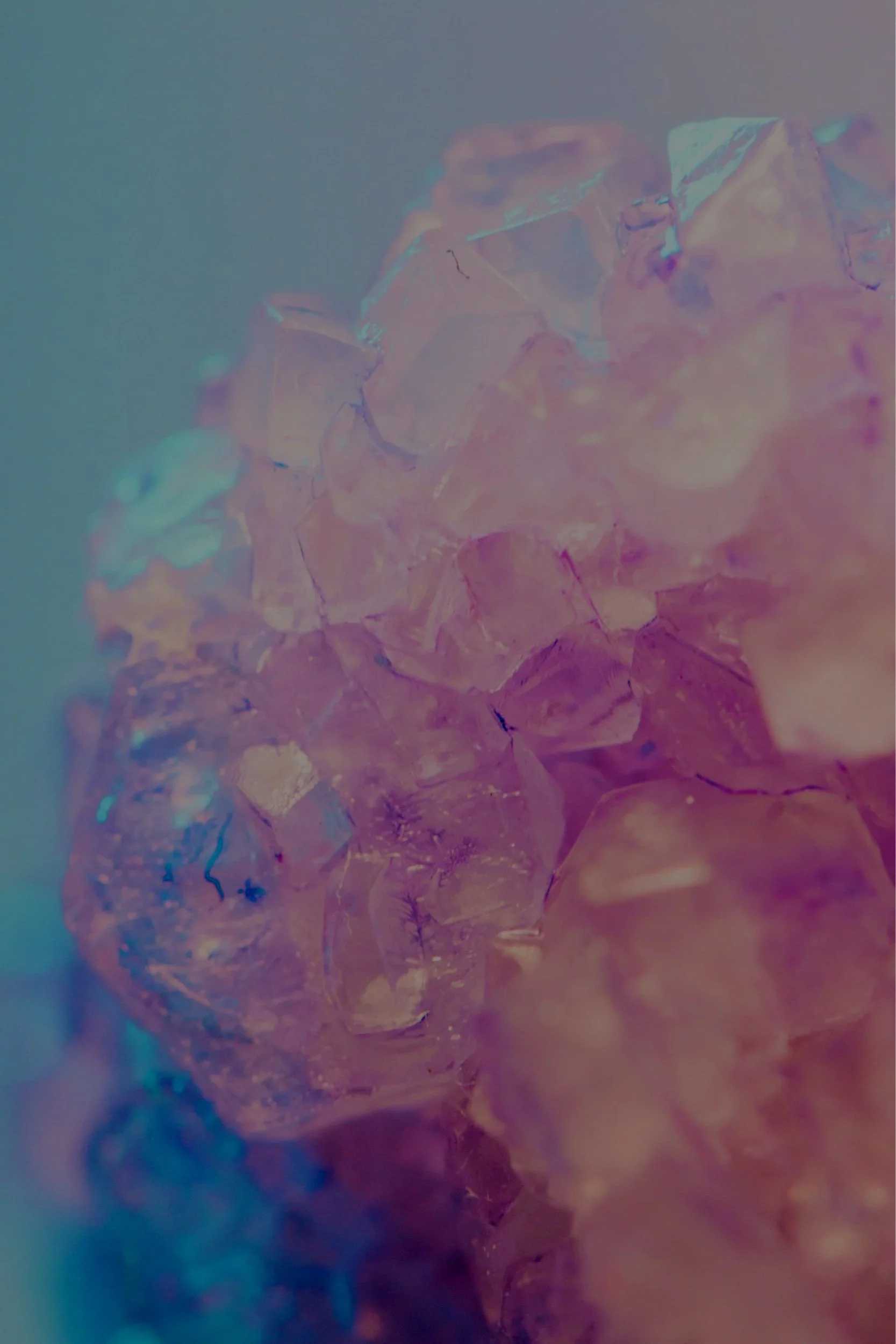 Close-up of iridescent, pinkish, translucent crystals with a soft blue background.