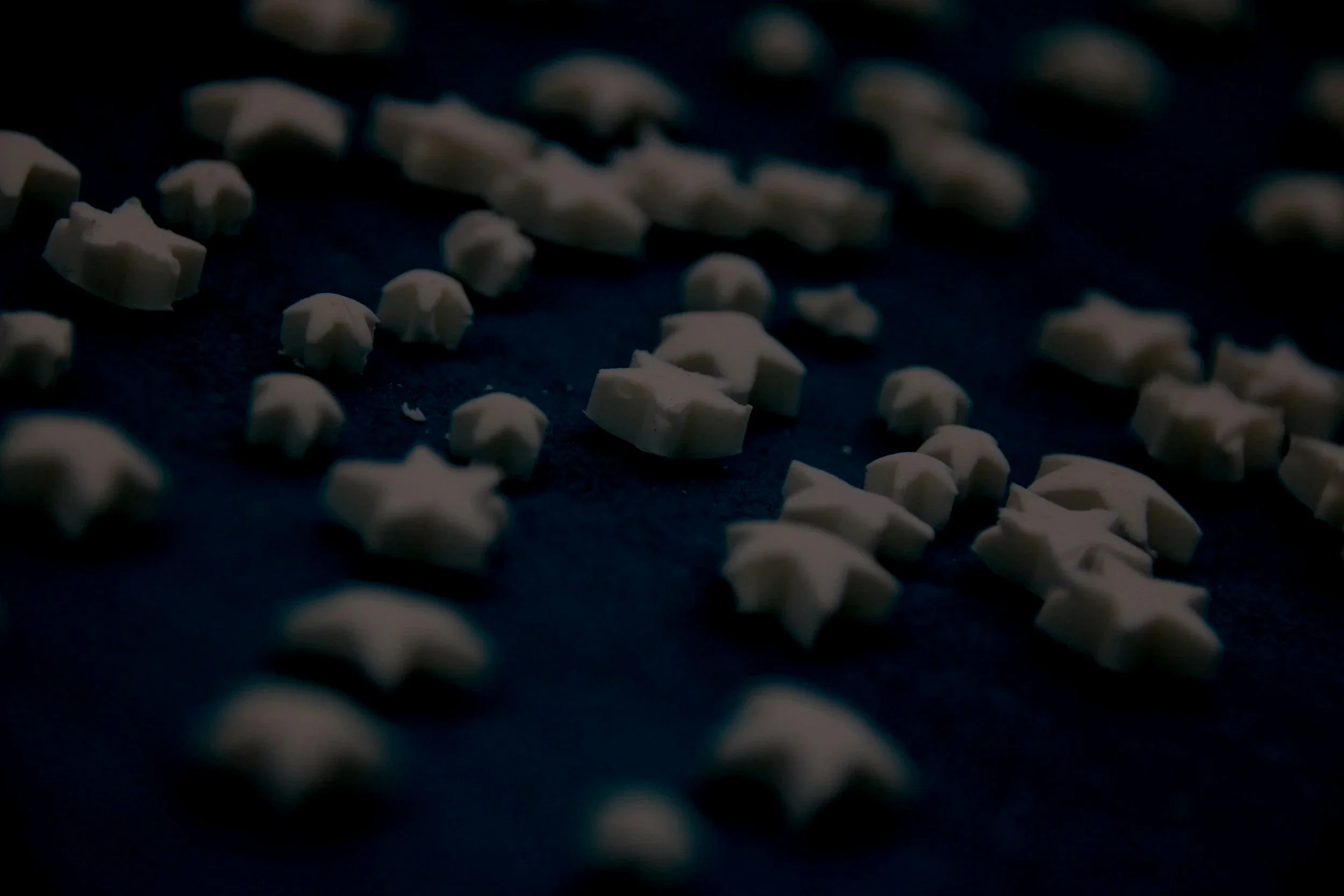 Various white plastic gaming tokens shaped like stars, moons, and other figures scattered on a dark surface.