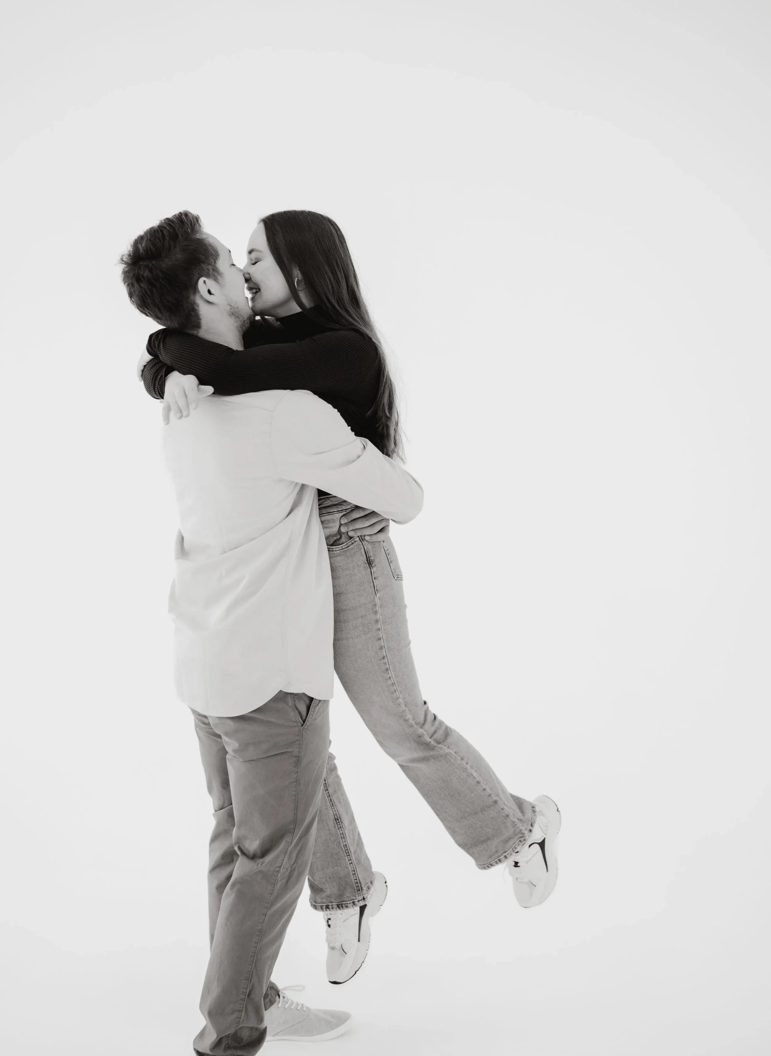 Ein junges Paar umarmt sich lachend vor einem weißen Hintergrund. Fotografiert von Rebecca Fotografie in Pforzheim in einem Fotostudio.