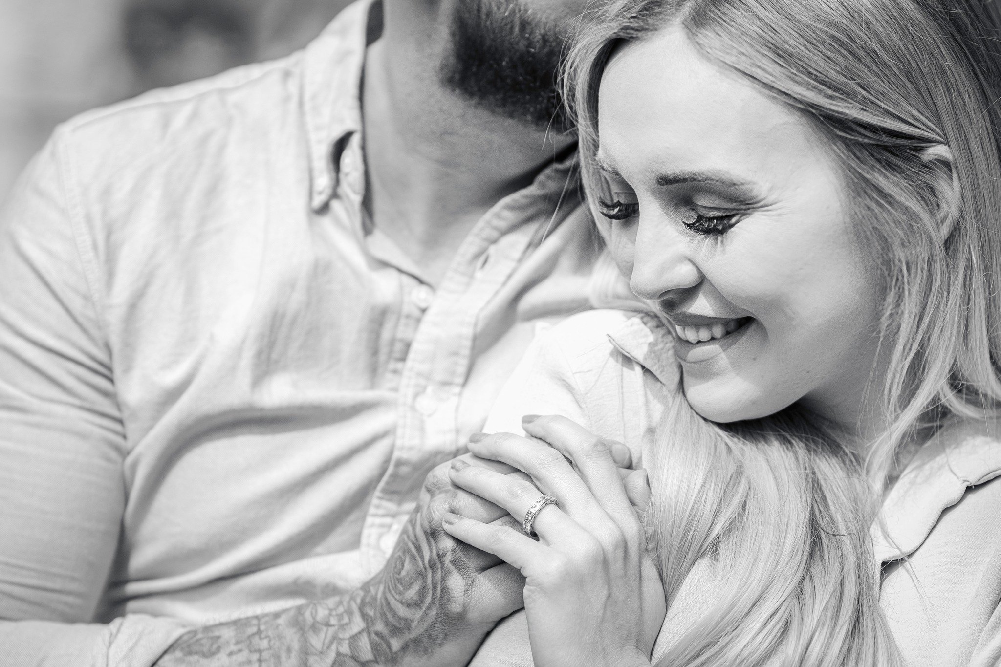 A couple smiling and embracing each other, with the woman showing her wedding ring on her finger.