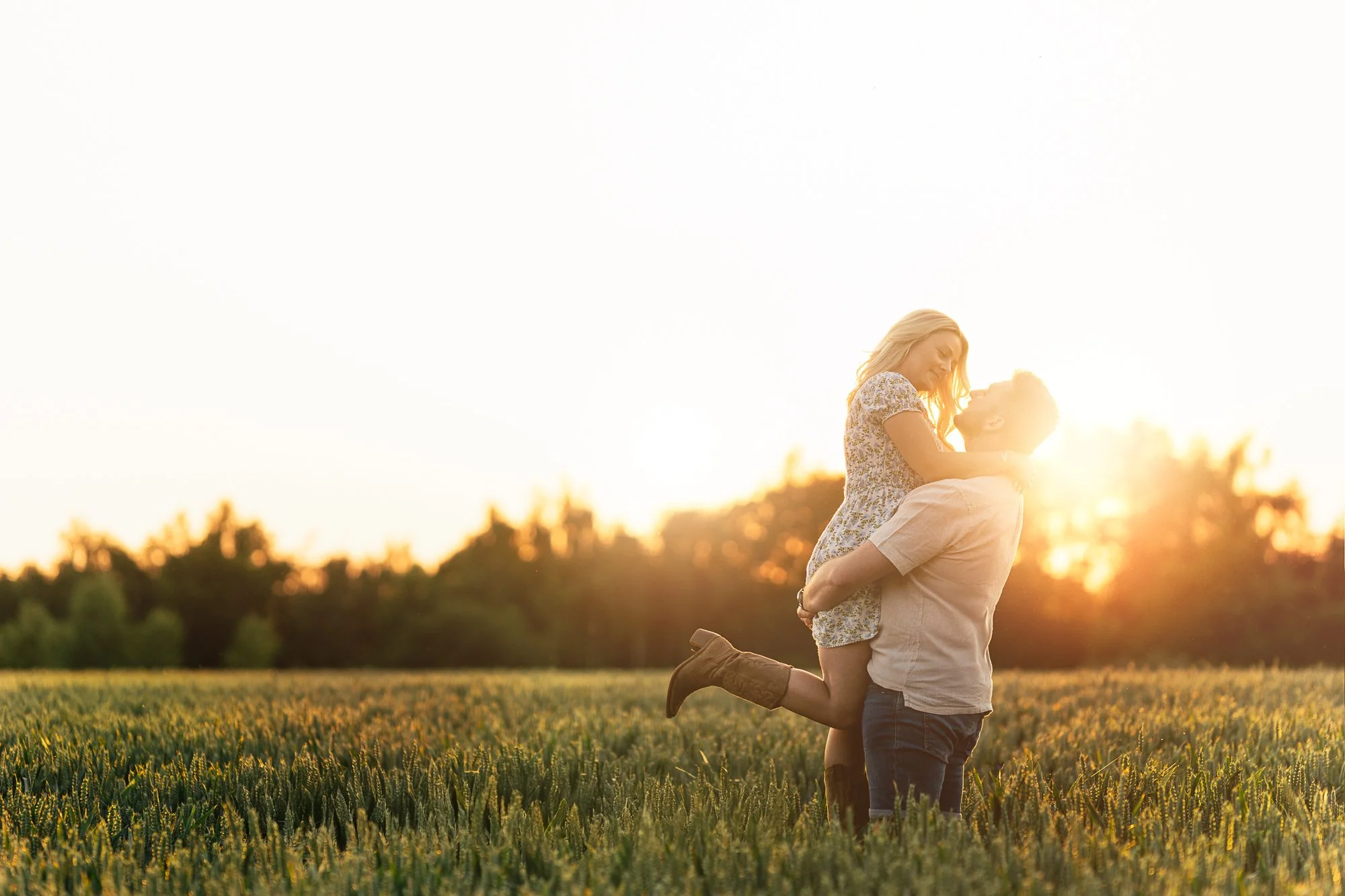 A couple in love, with the man lifting the woman in a wheat field at sunset.