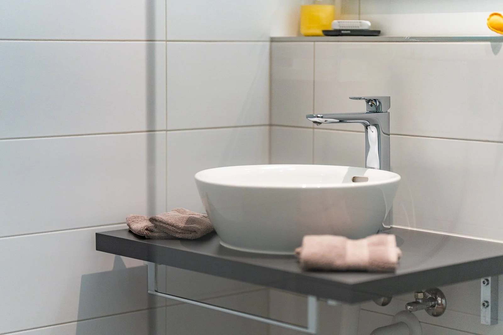 Waschbecken in einem Badezimmer mit Handtüchern auf der Ablage und einer Wasserleitung
