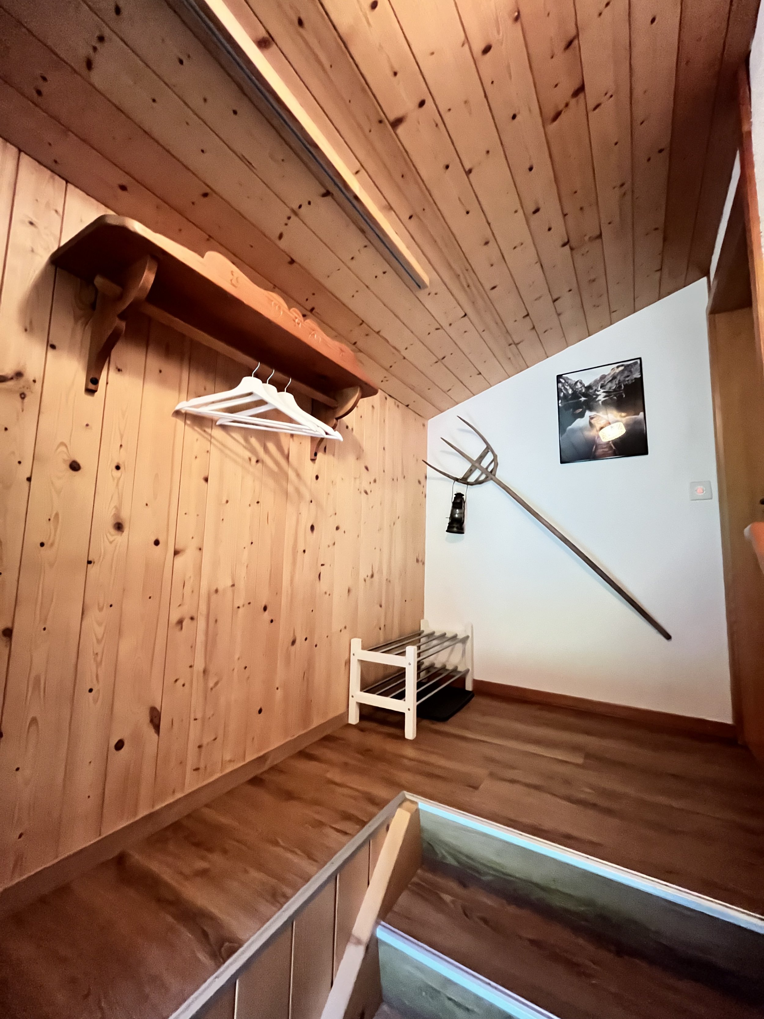 Ein Raum mit Holzwände und -Decke, Wanddekoration mit einer Kelle, einem Hut, einem Bilderrahmen und einem abgehängten Licht.