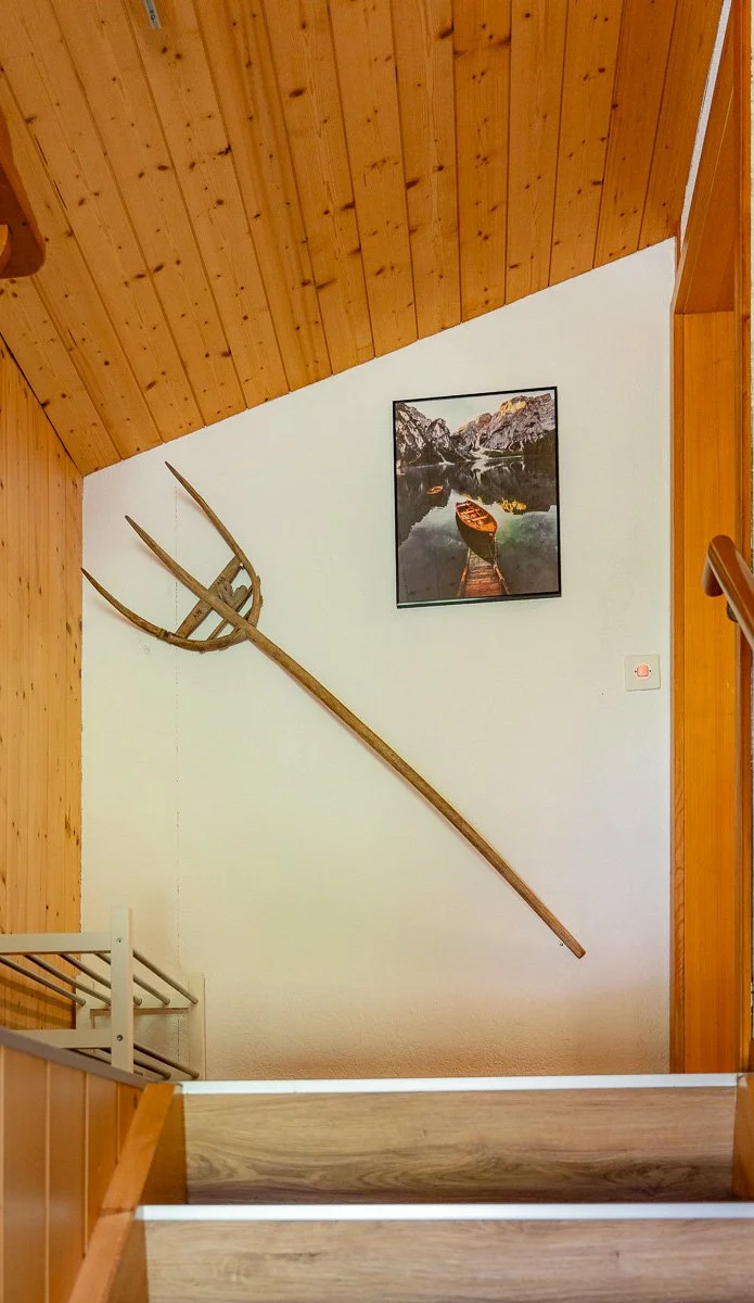 Ein Wandbild mit einem alten Heugabel und einem Foto von einem Boot auf einem See inmitten von Bergen.