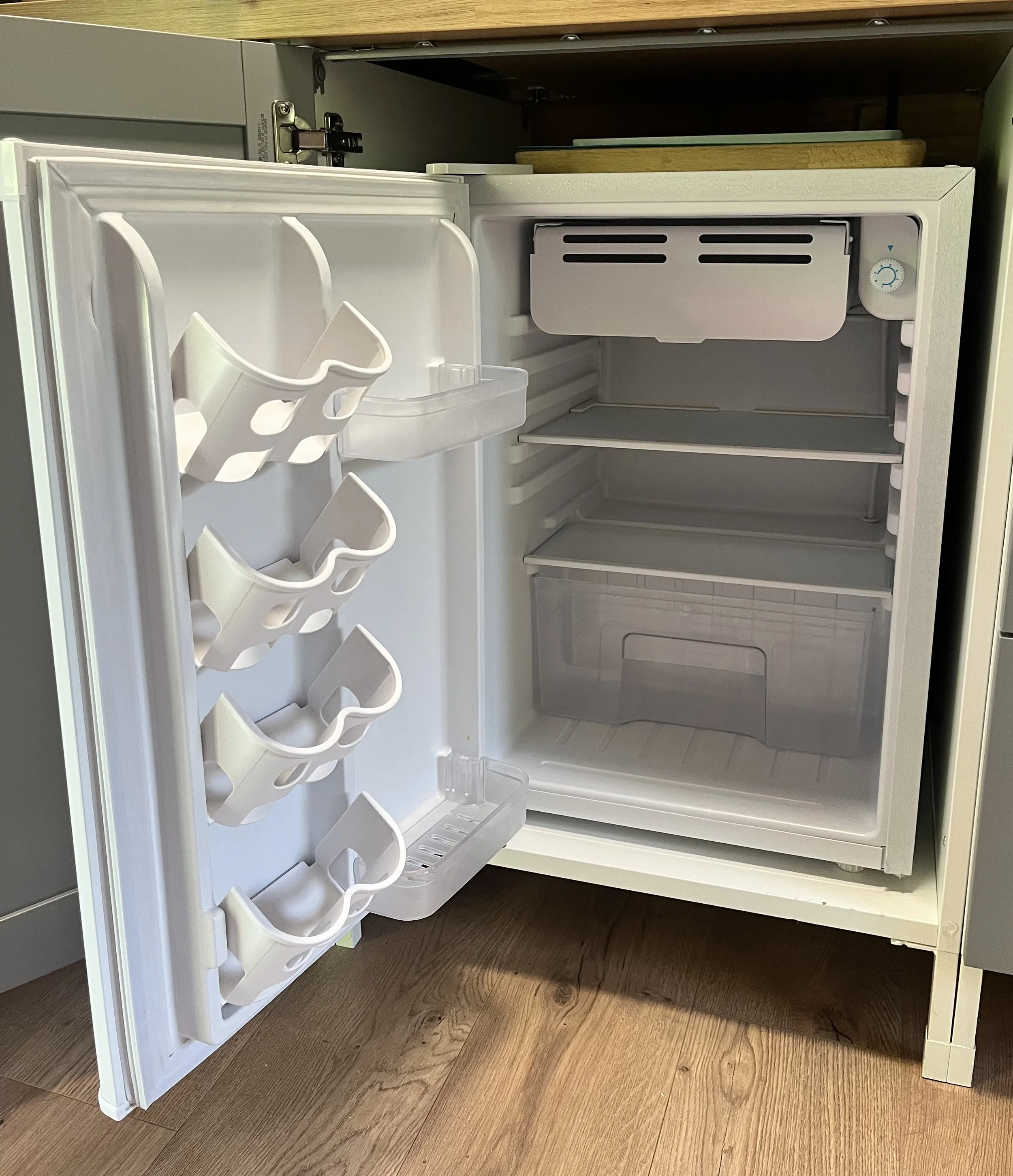 Ein leeres Kühlschrank mit offenem Tür, Innenfächern und Türablagen.