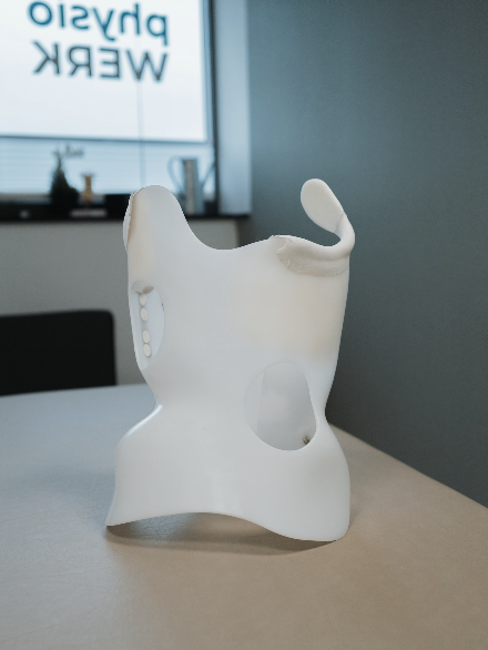 Weißes, skulpturartiges Objekt mit Aussparungen und abstehenden Elementen auf einem Tisch