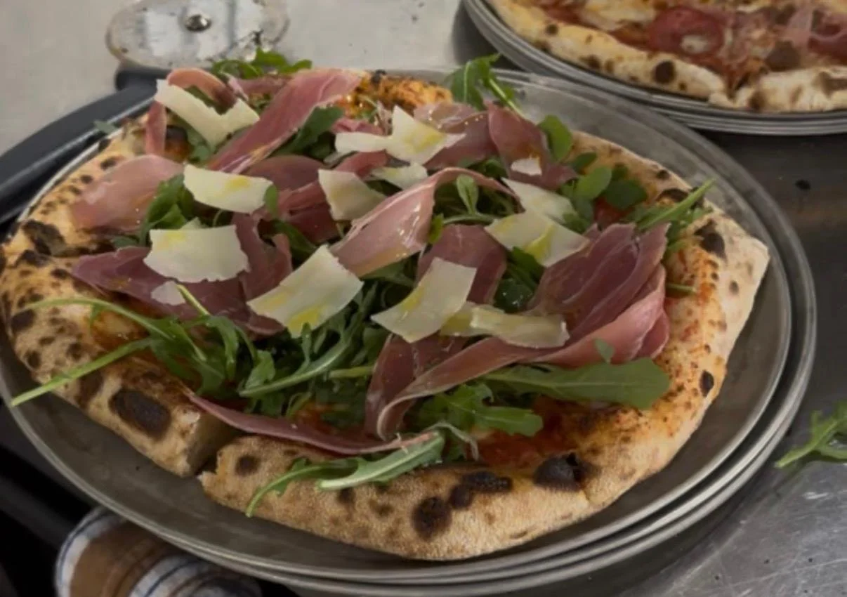 Wood-fired pizza topped with prosciutto, rocket and shaved parmesan