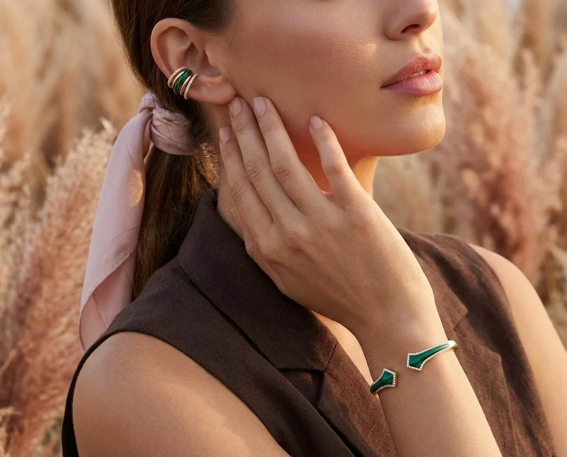 A close up portrait shot of a woman wearing a 5 band cuff with 1 malachite, 2 diamond and 2 yellow gold bands, as well as a arrow themed malachite with diamond edges and yellow gold bangle.